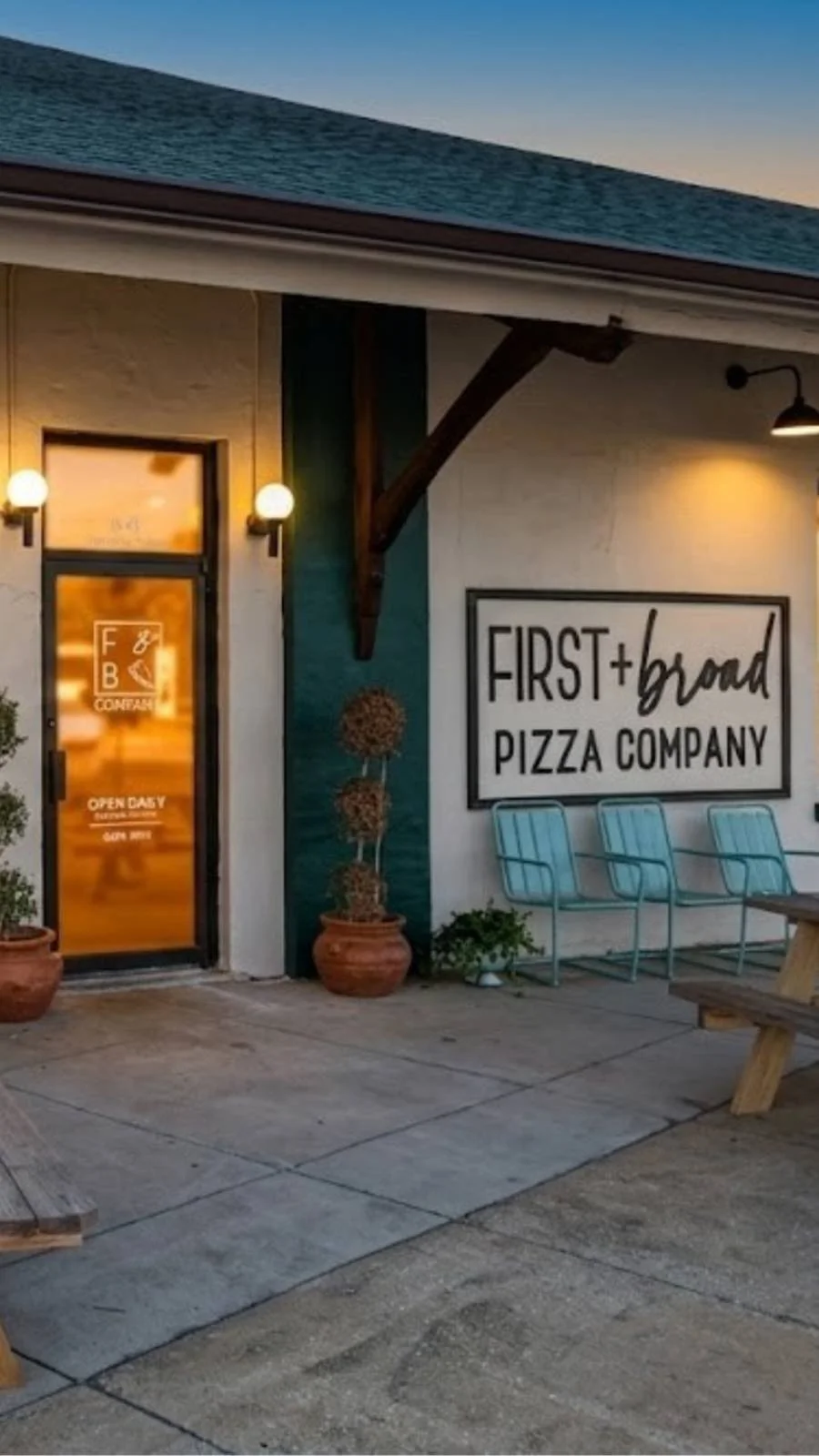 Exterior of First and Broad Pizza Company with patio tables, umbrellas, and storefront signage.
