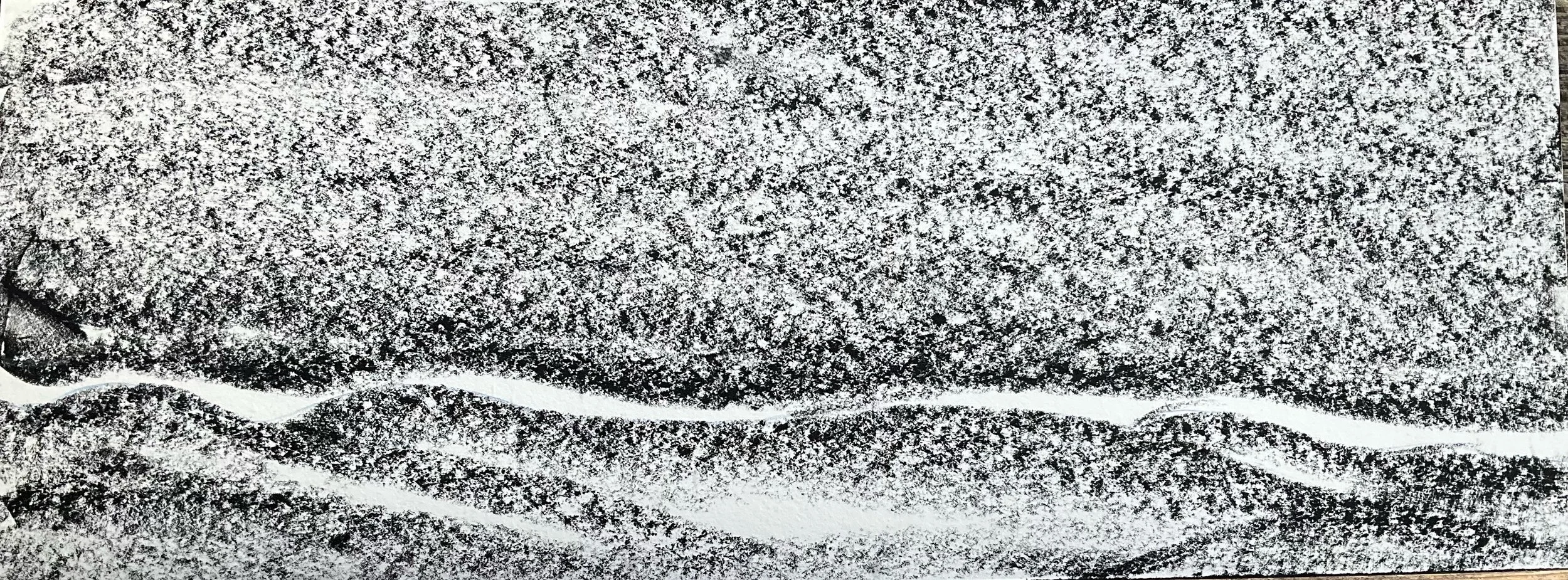 Close-up of a rough, textured surface with black and white speckled appearance and wavy lines.