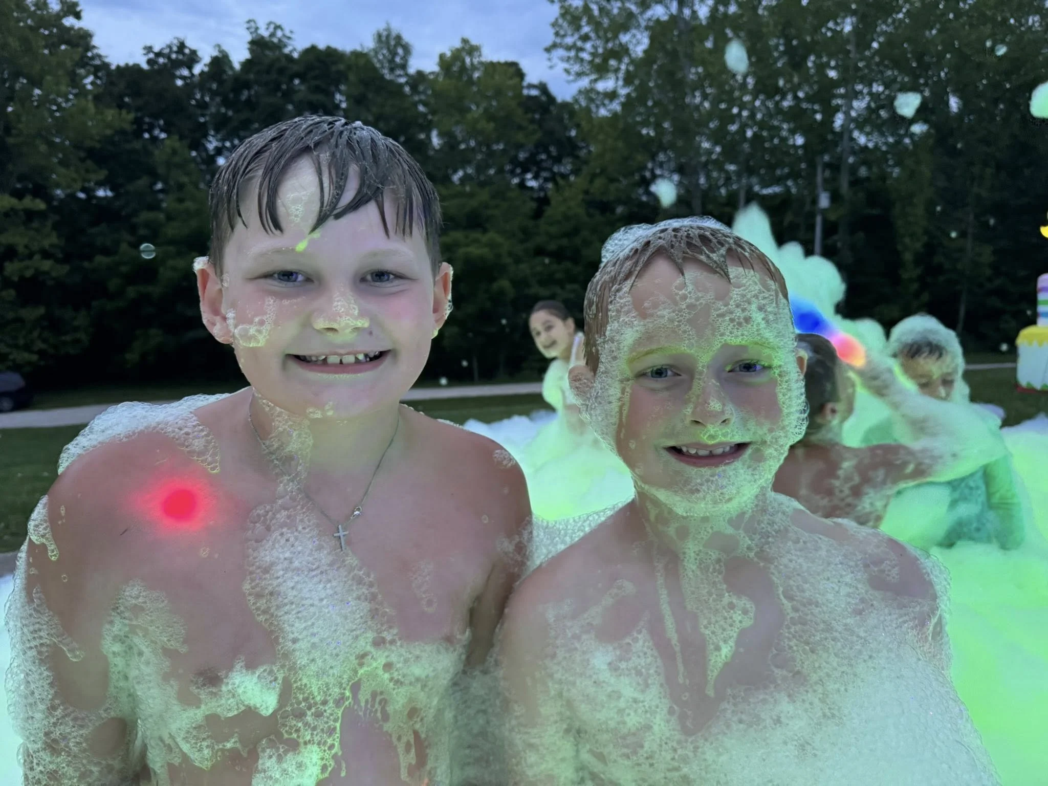 Children playing in a bubble-filled outdoor area during twilight.