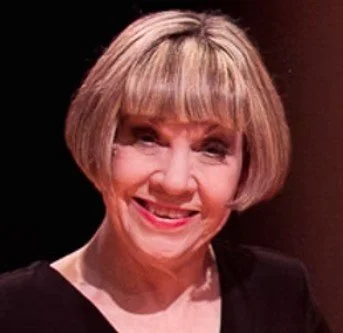 A woman with short blonde hair smiling at the camera.