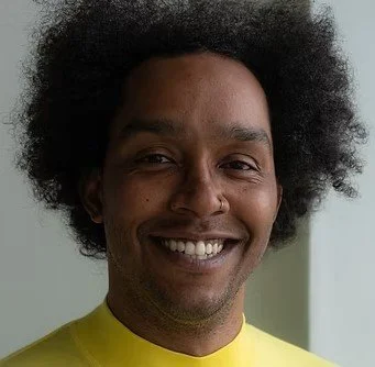 Portrait of a man with curly hair smiling at the camera.