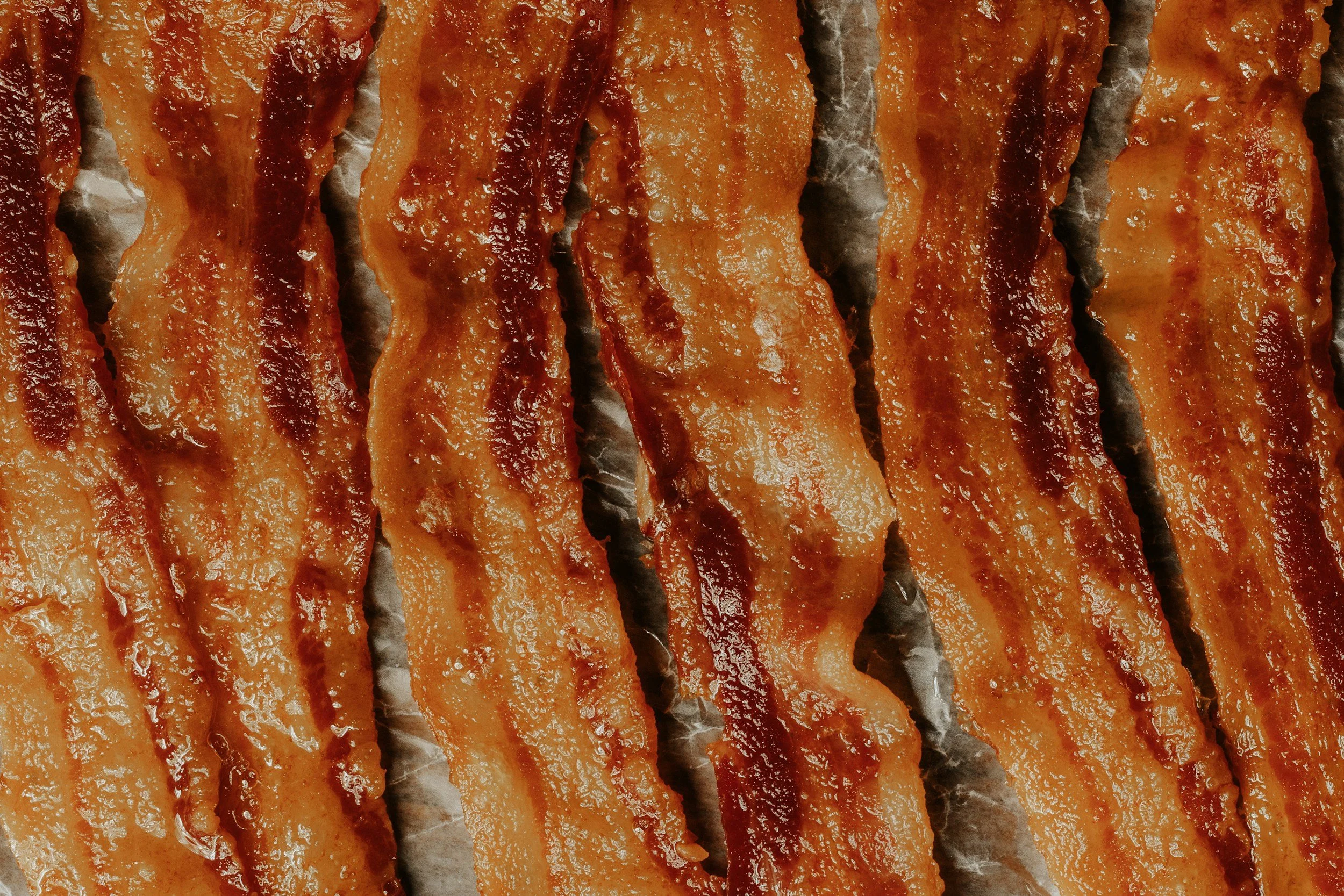 Multiple strips of crispy cooked bacon layered side by side.