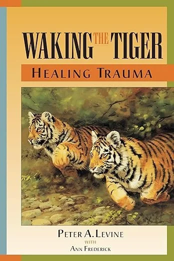 Book cover titled 'Waking the Tiger: Healing Trauma' by Peter A. Levine, with co-author Ann Frederick, featuring an illustration of two tigers lying on grass.