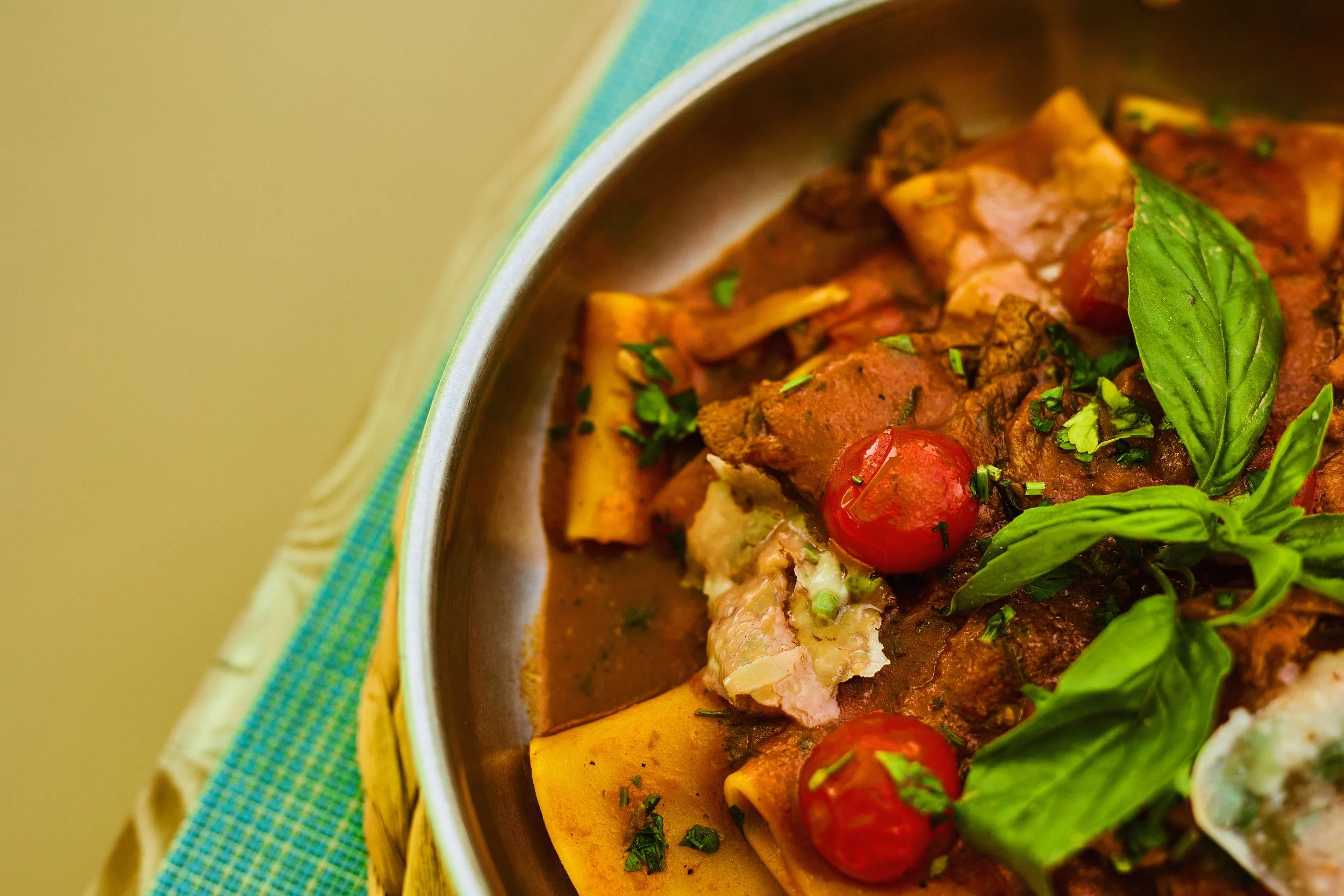 Close-up of a bowl of pasta with tomato, basil, and tomato sauce garnished with herbs.
