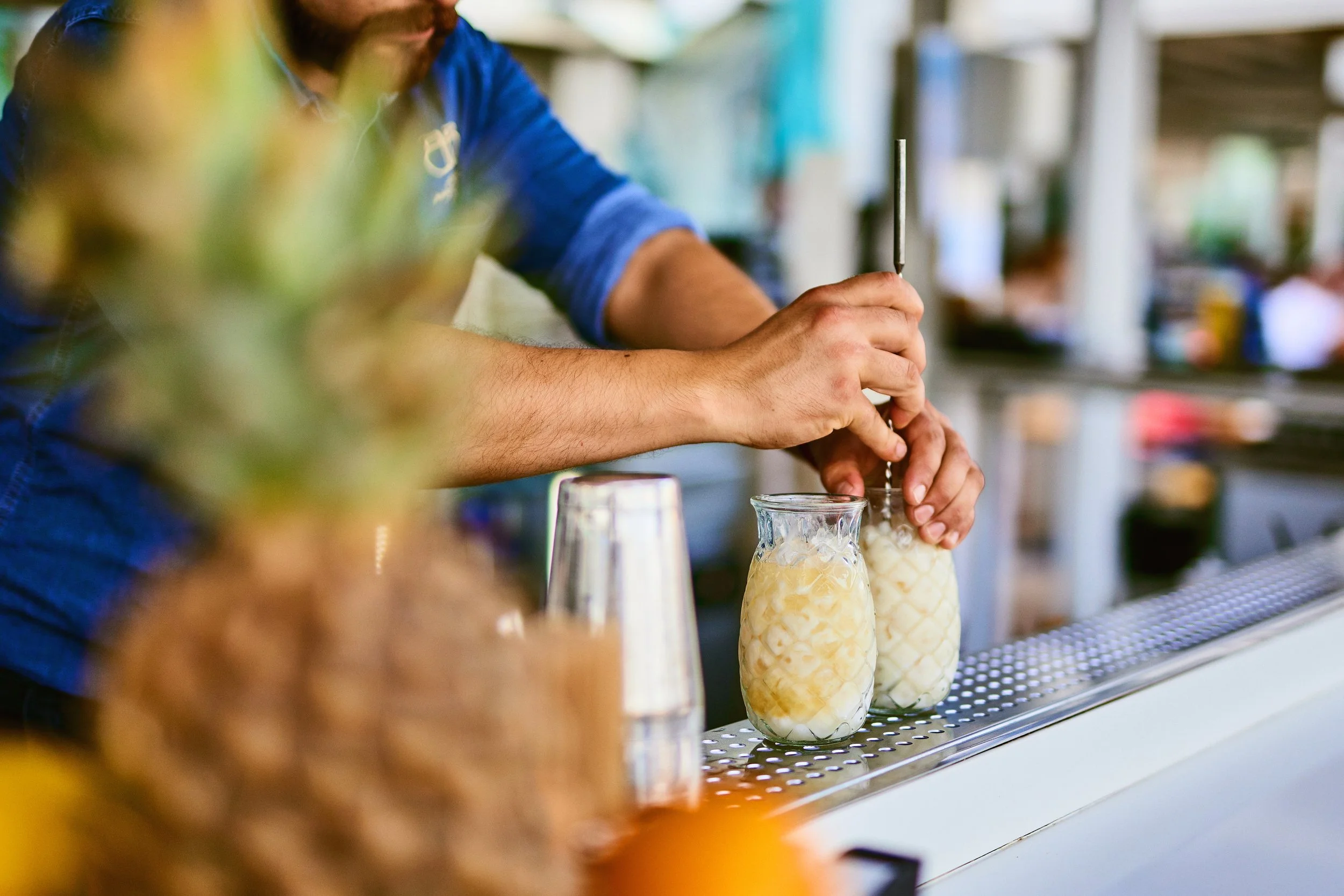 A bartender preparing drinks with ice in a bar or cafe setting.