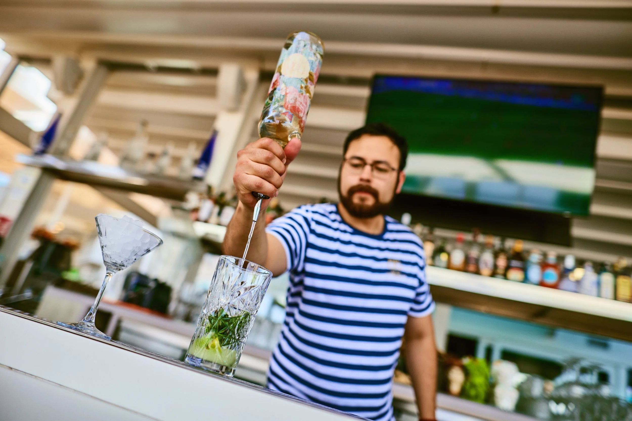 Bartender pouring a cocktail into a glass at an outdoor bar
