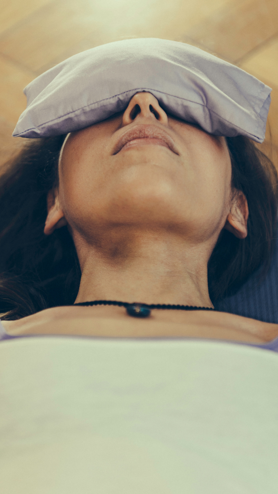 A woman resting with an eye pillow during a guided relaxation practice.