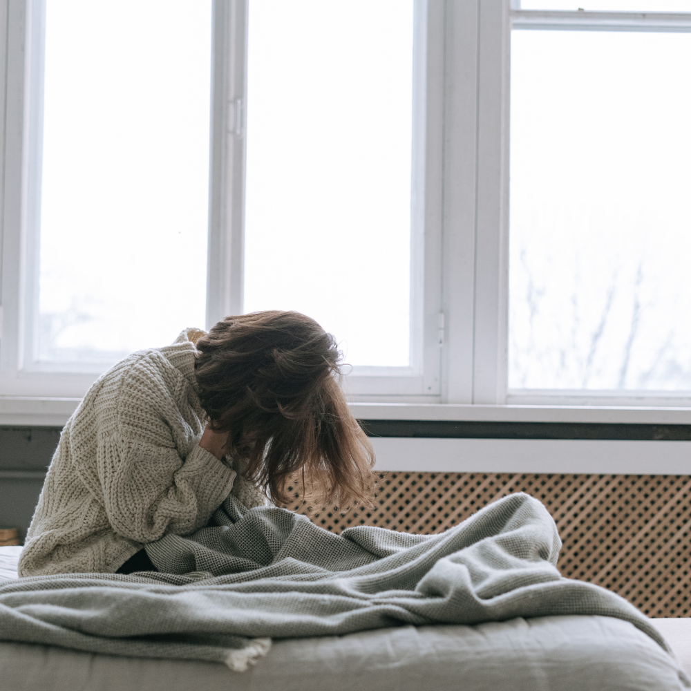 Person sitting on a bed during a slow day of neurodivergent healing while resting and listening to their nervous system.