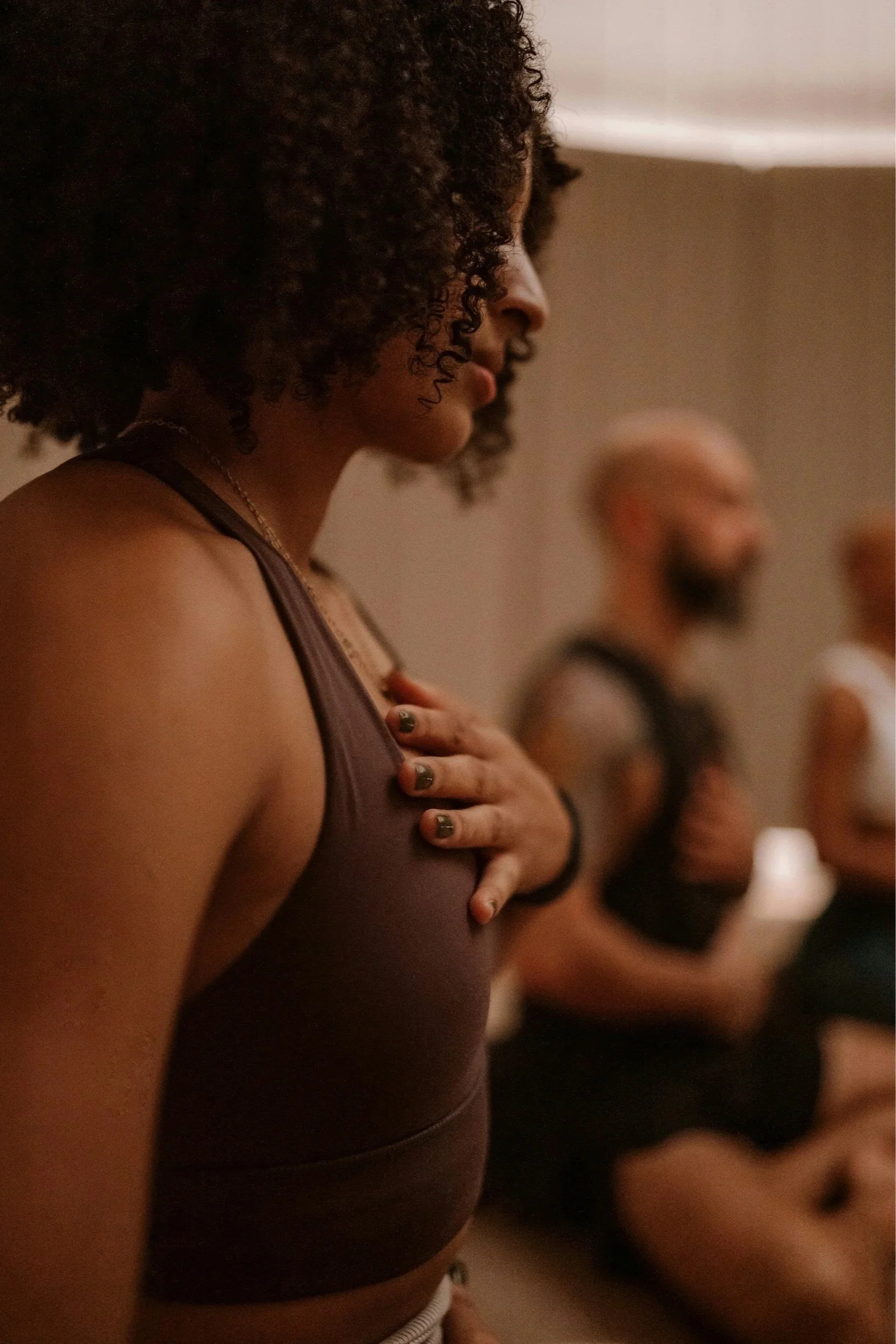 People breathing, eyes closed, hands on their heart and belly in a group setting