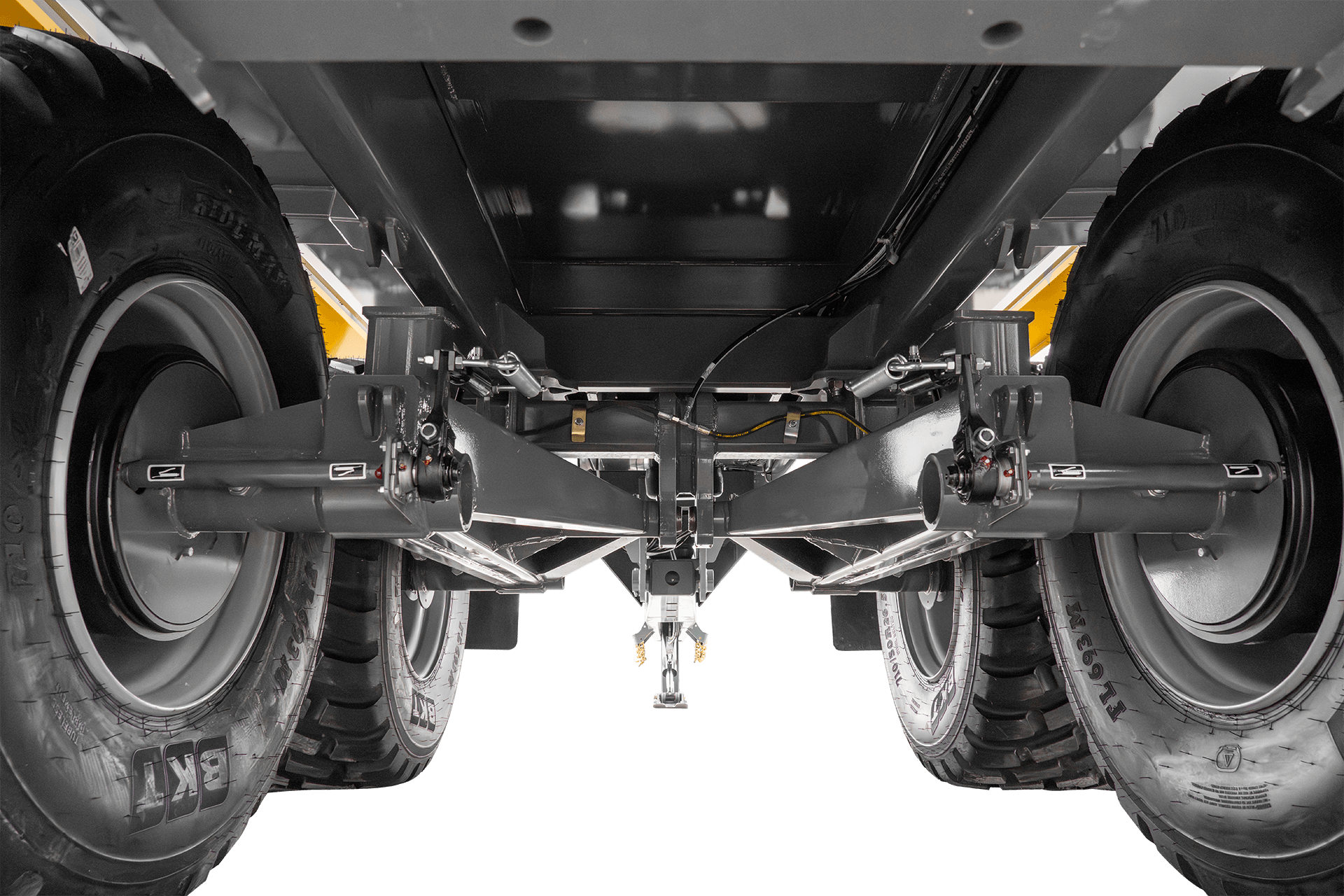 Underside of a vehicle showing large tires, suspension system, and mechanical components.