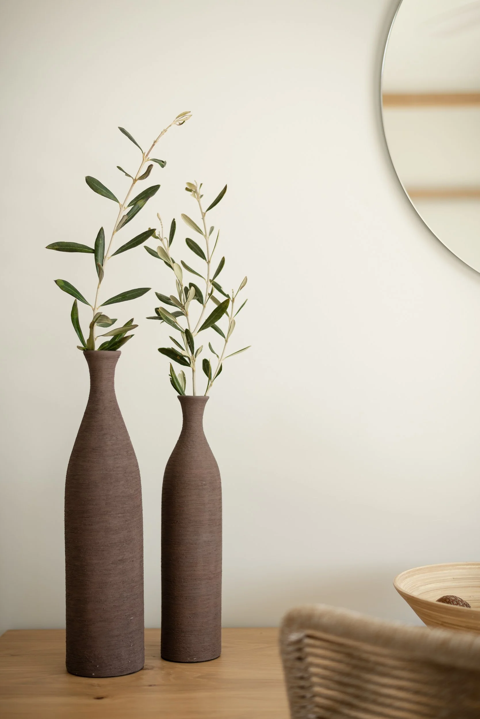 Two tall, brown ceramic vases with green leafy branches on a wooden surface. Hotels, Villas, Airbnb photography. Corfu, Greece.