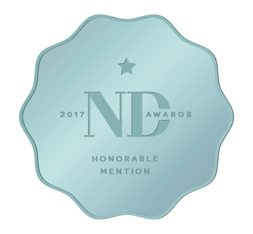 A blue award badge with an irregular shape, featuring a star at the top, the text '2017 NDC AWARDS', and 'HONORABLE MENTION' at the bottom.