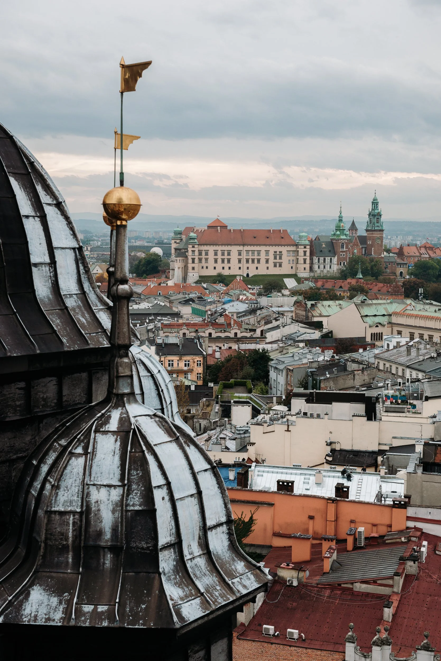 View of the historic city of Prague with rooftops in the foreground and Prague Castle in the distance.