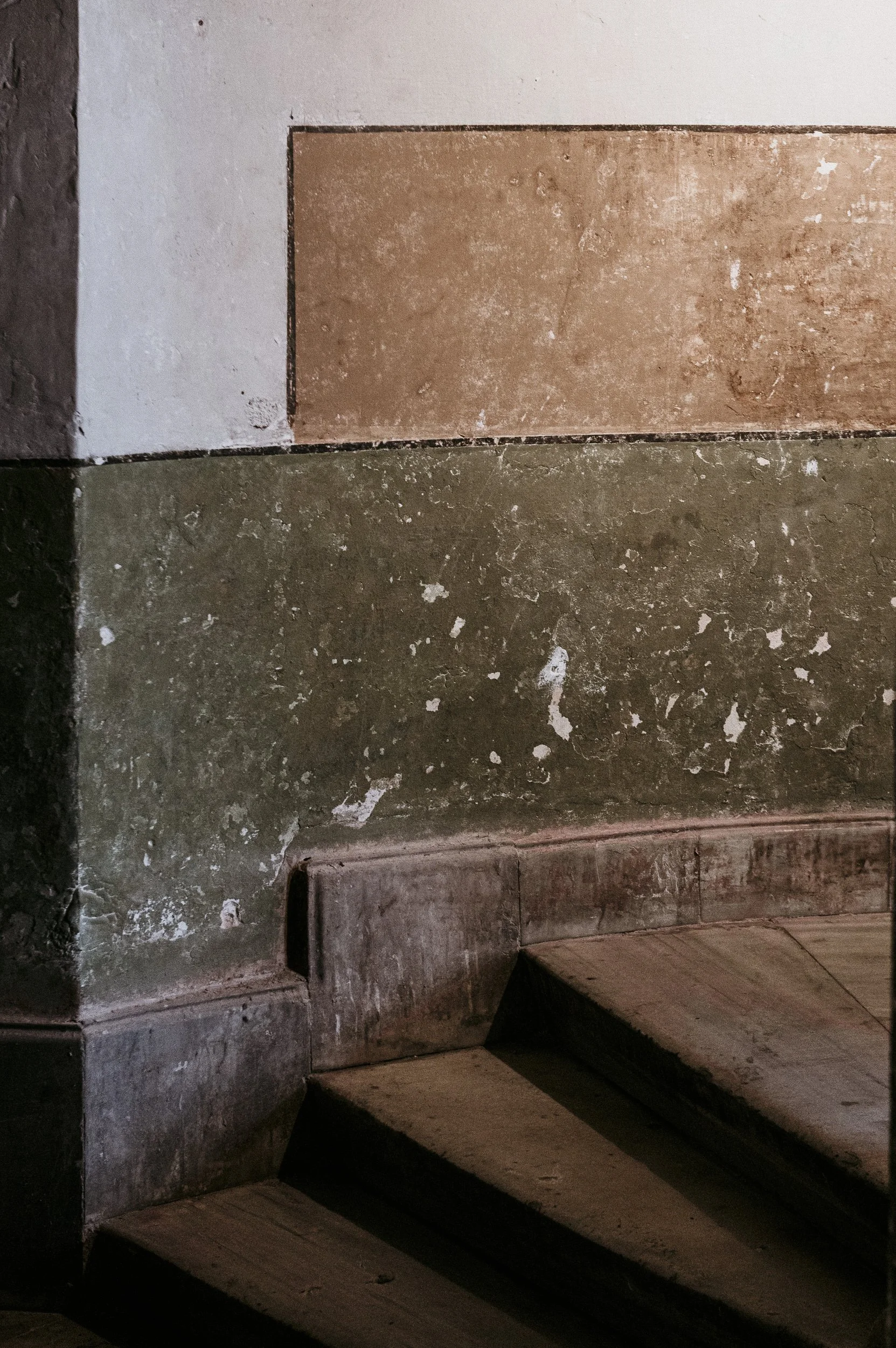 Concrete staircase with a weathered wall and a decorative tile above.