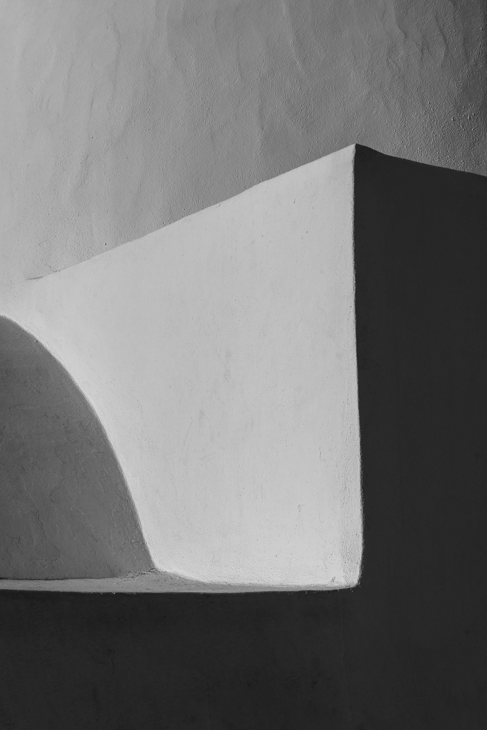 Black and white photograph of a minimalist geometric structure with sharp angles and contrasting light and shadow.