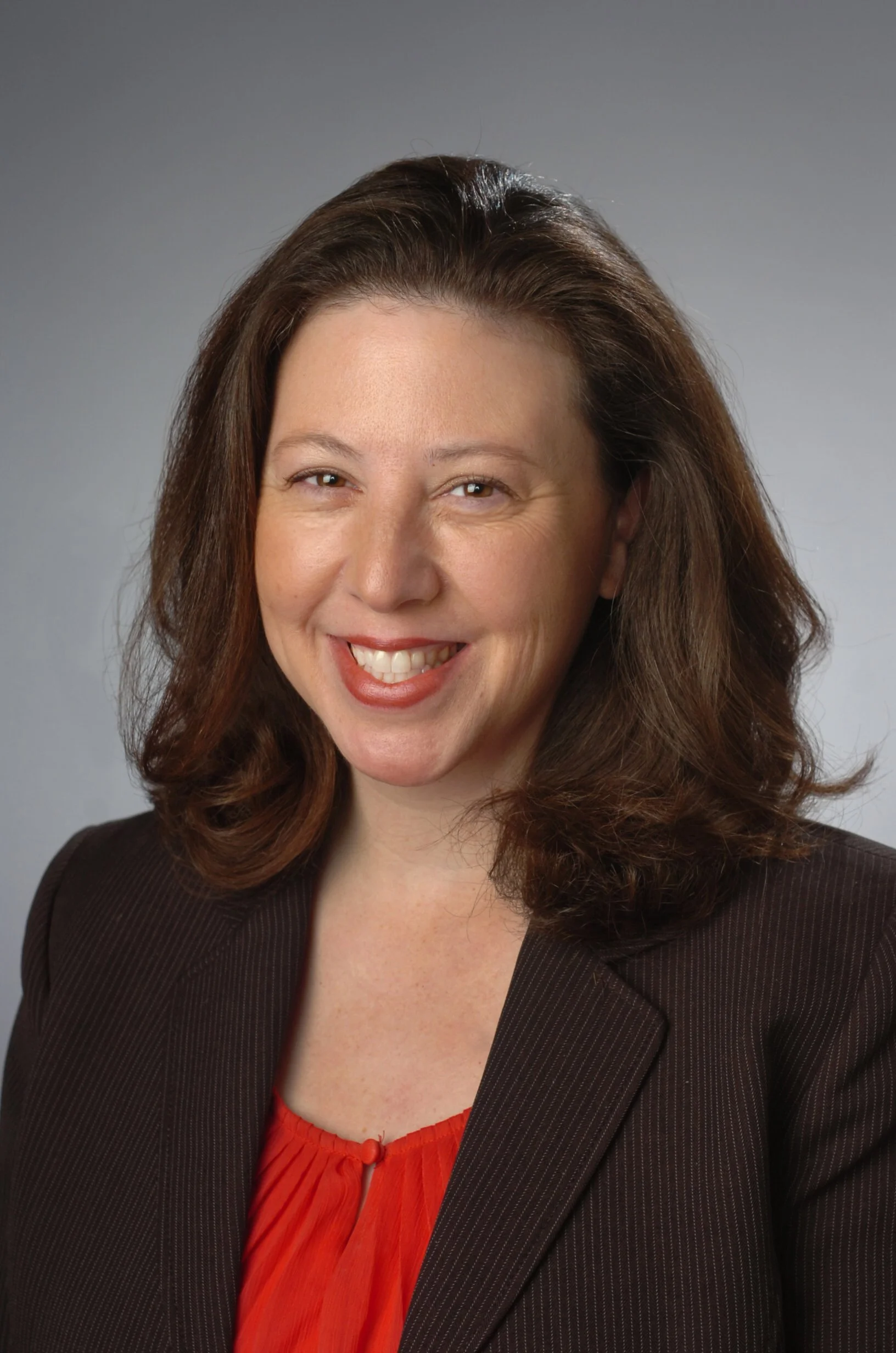 Amy Manley wearing dark suite jacket and red top.