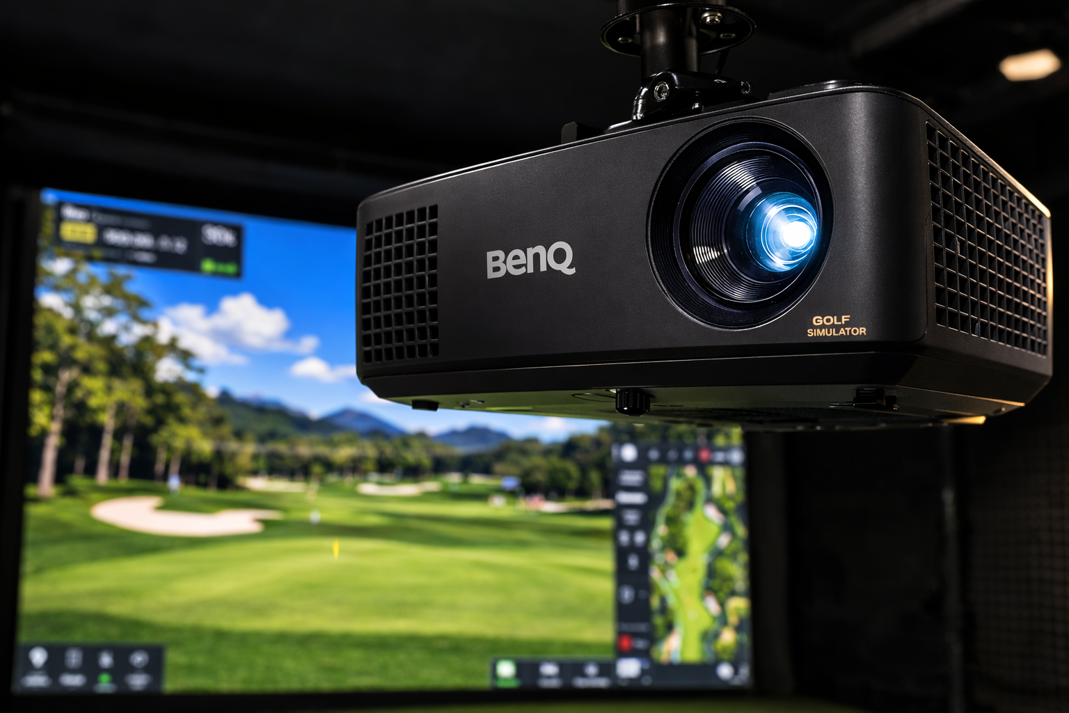 A BenQ golf simulator projector mounted on the ceiling, projecting a golf course onto a screen, with a computer monitor displaying golf course data in the background.
