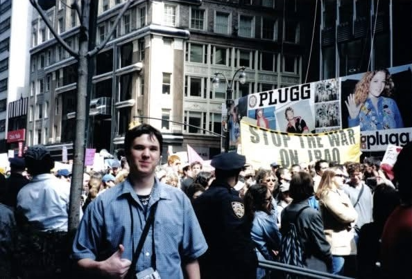 A young Thomas Wingate, candidate for democratic central committee for district 46, poses in front of a banner that reads "Stop the War in Iraq"