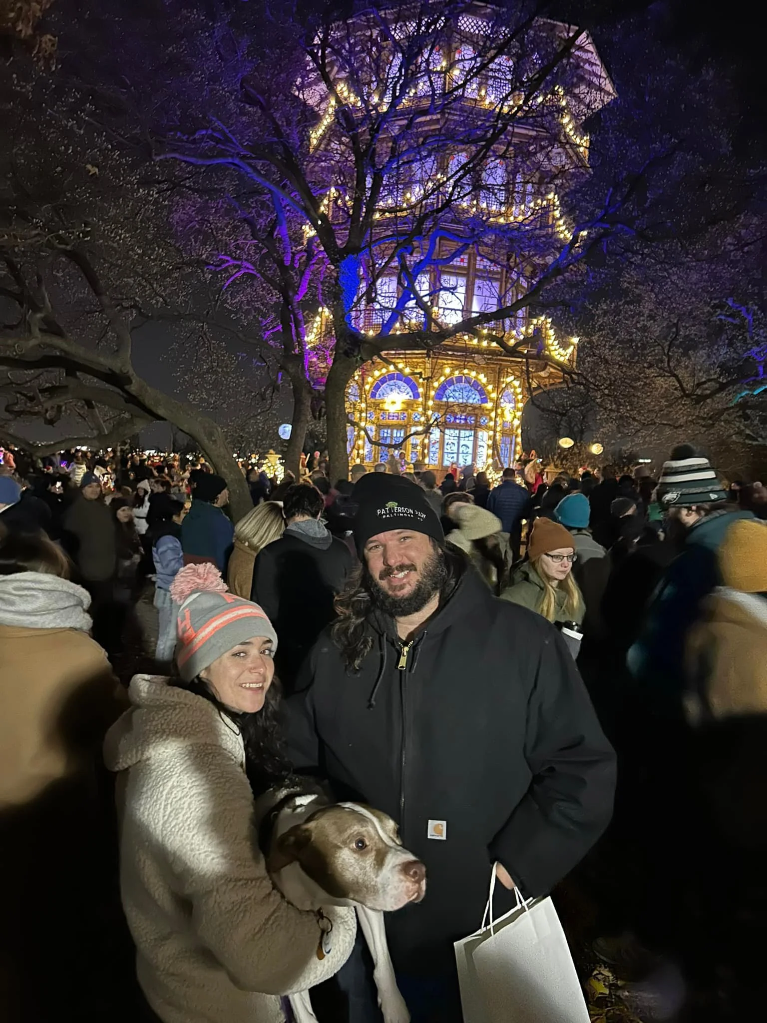 Candidate Thomas Wingate, his wife and dog are standing at night in front of the Patterson Park Observatory during a holiday lighting show