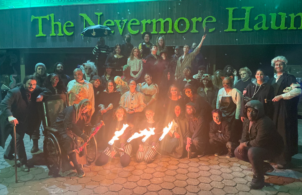 Staff of The Nevermore Haunt posing in front of the haunted house. Candidate Thomas Wingate appears in costume in the far left of the group photo
