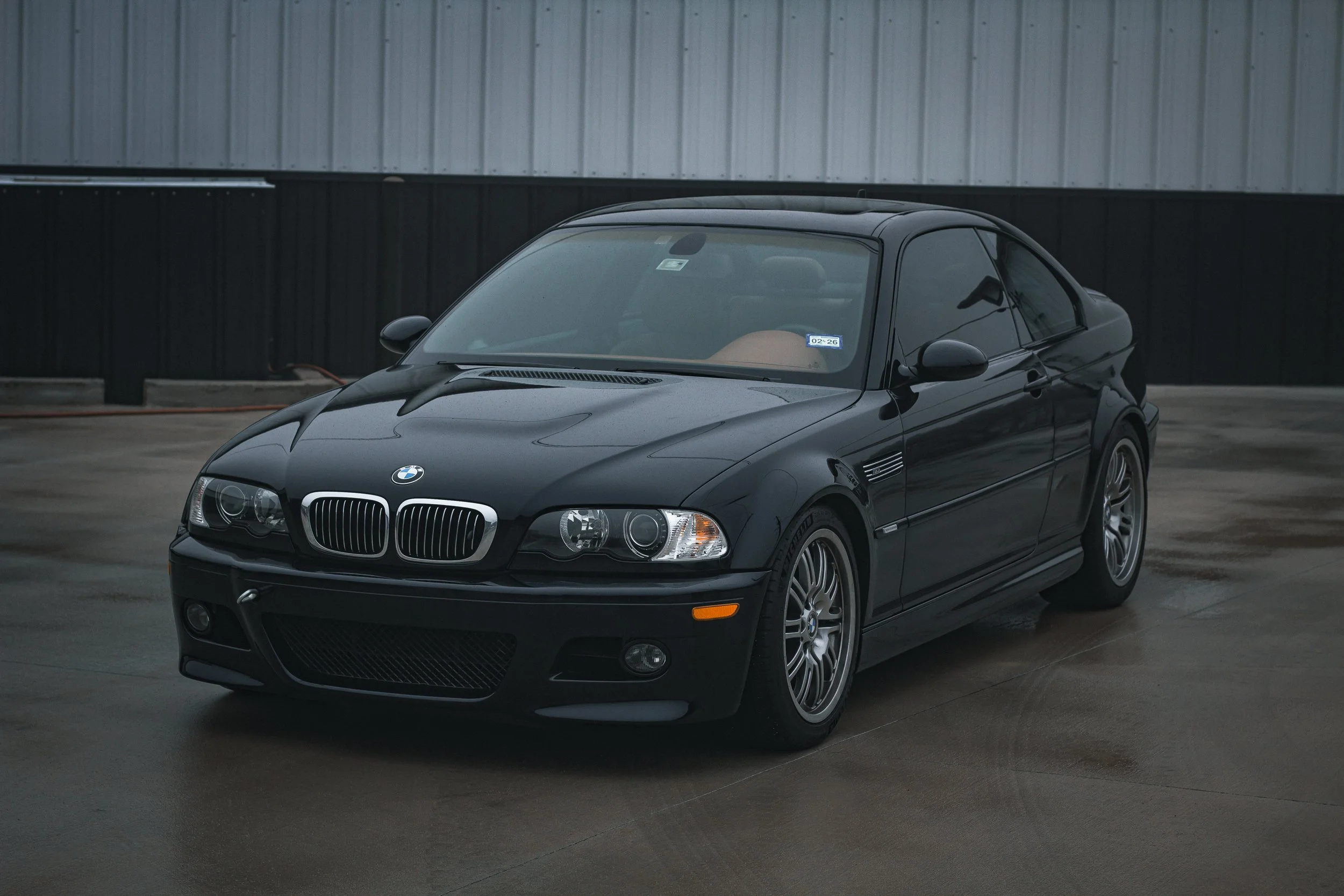 Auto negro BMW en un estacionamiento cubierto.