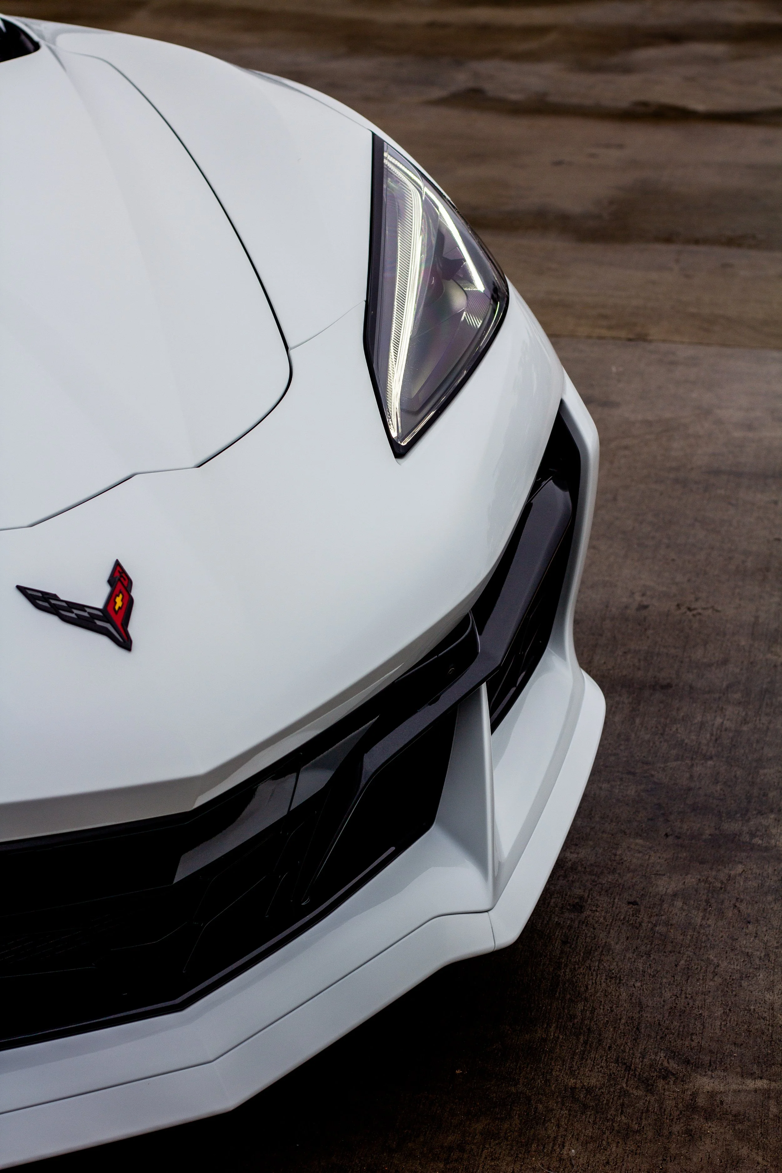 Parte frontal de un automóvil deportivo blanco, mostrando el logo de Chevrolet en el capó y un diseño aerodinámico con líneas angulosas.