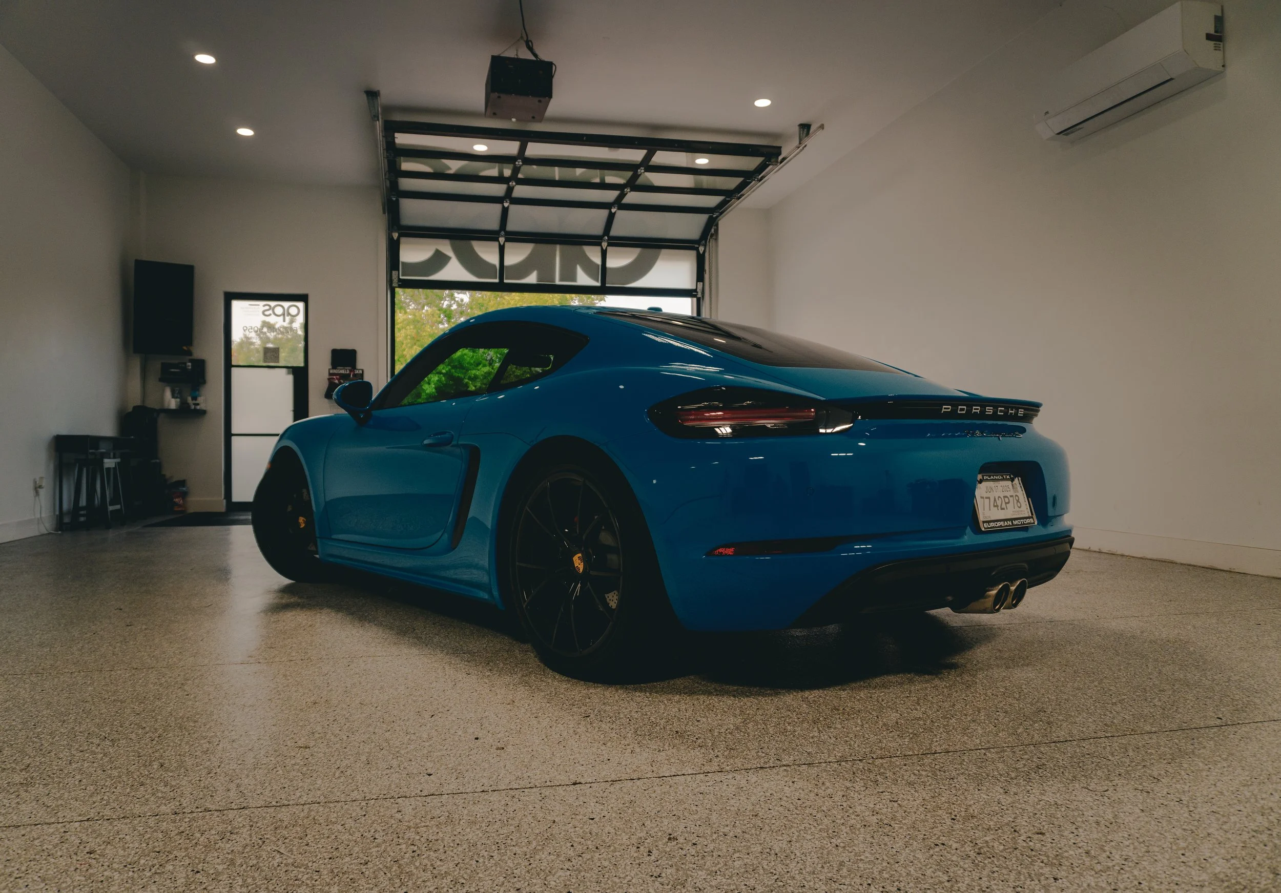 Coche deportivo Porsche azul en un garaje moderno.