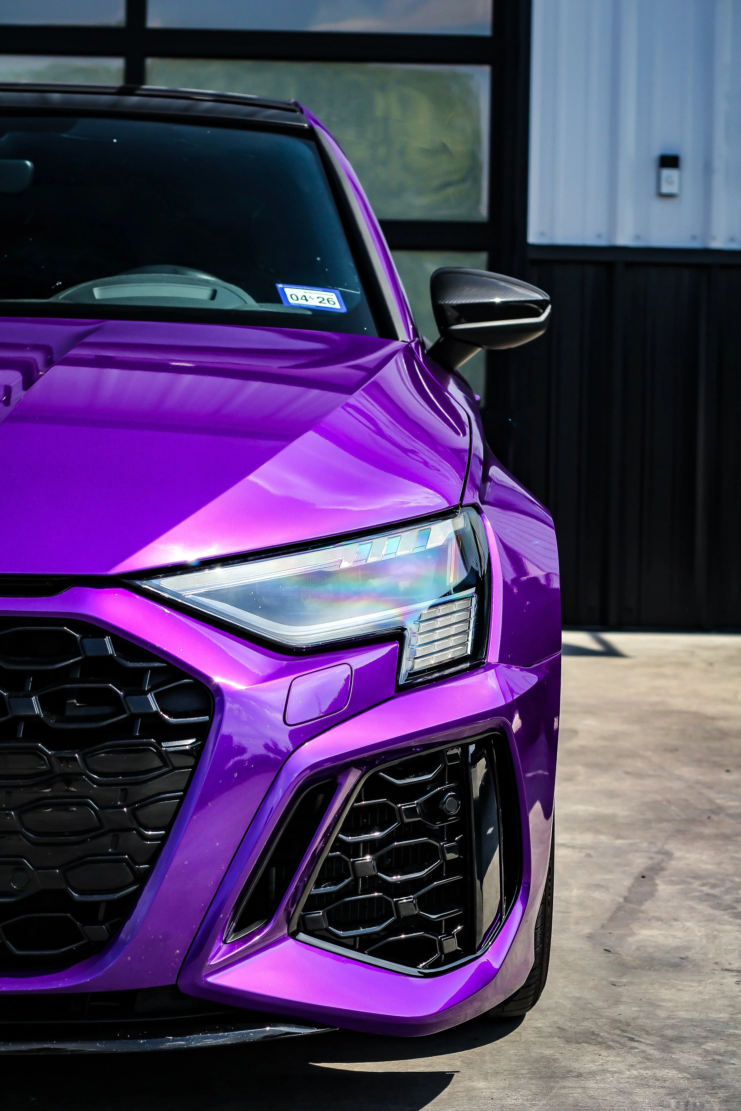 Primer plano de parte frontal de un automóvil deportivo de color morado en un garaje.