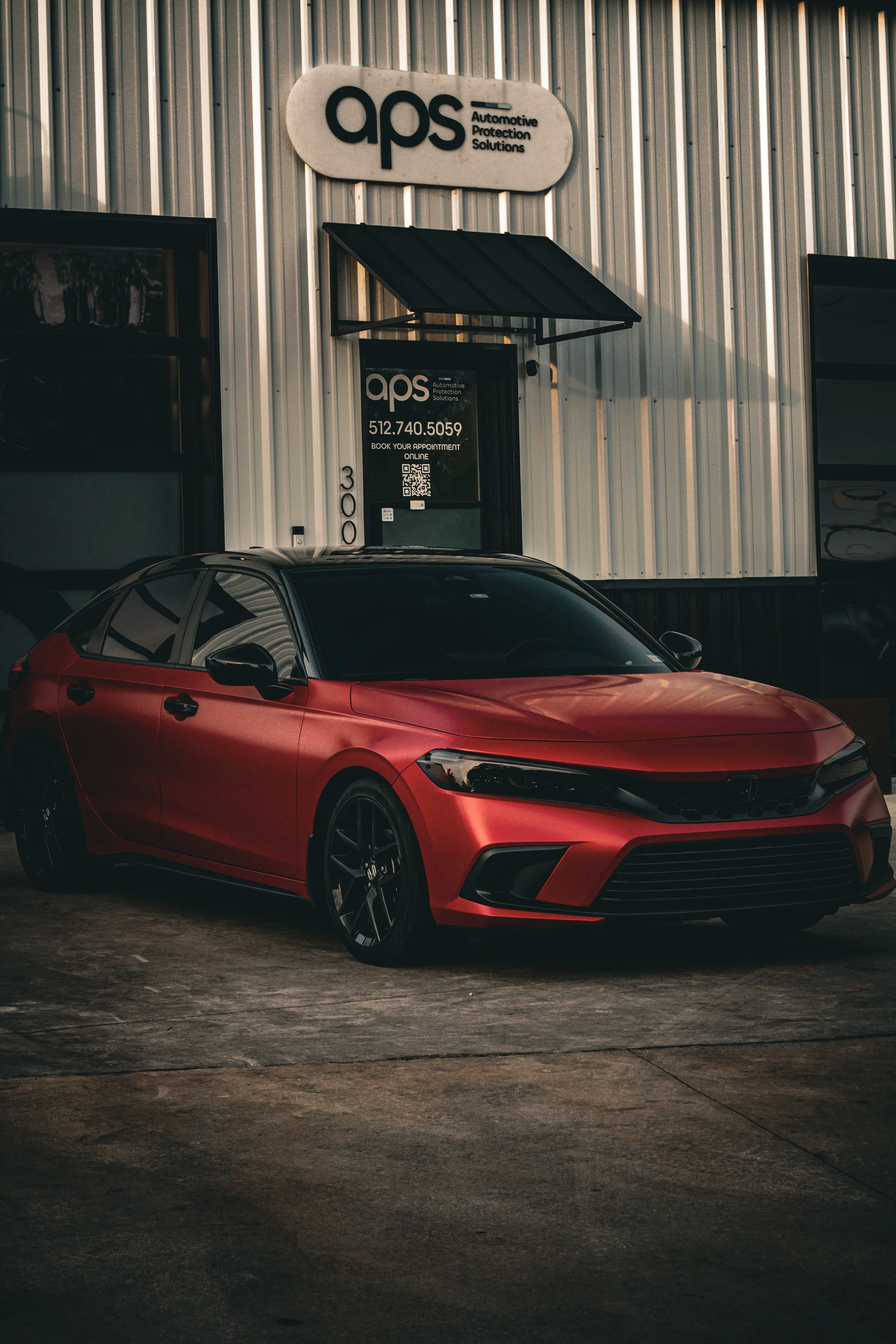 Auto rojo estacionada frente a un negocio de soluciones de protección automotriz. 