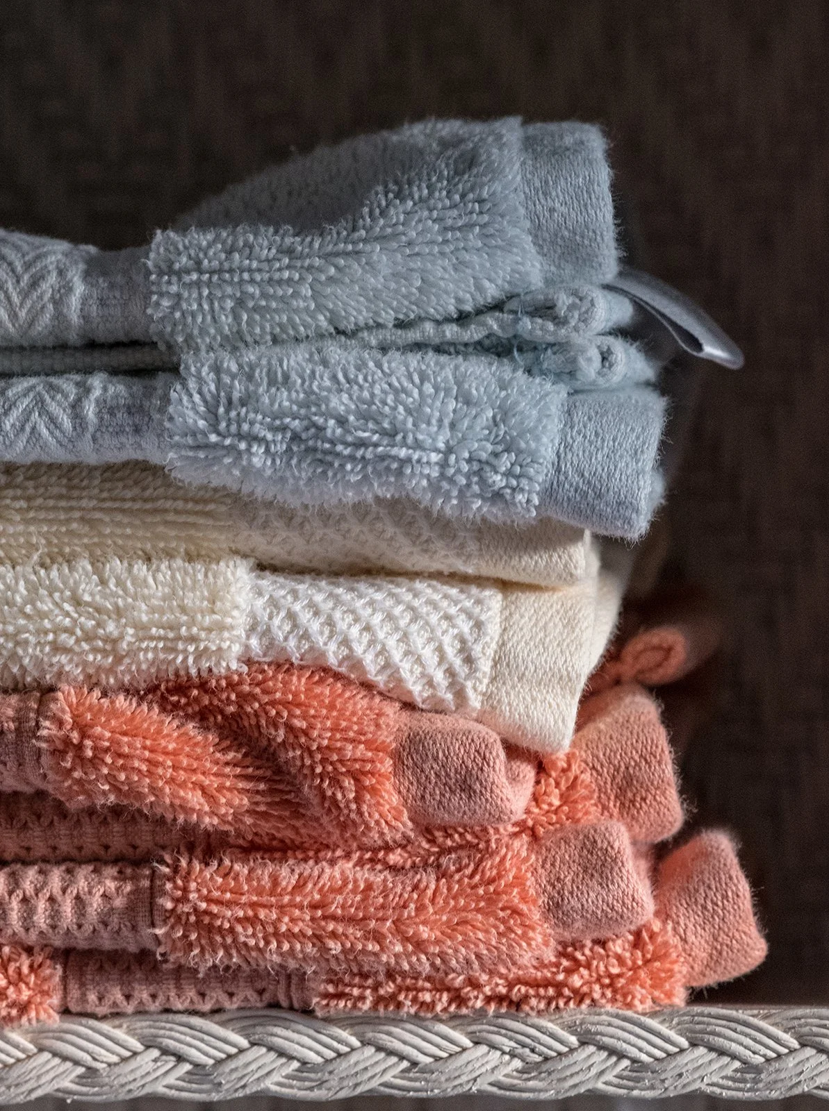 Stacked folded towels in gray, cream, and coral colors