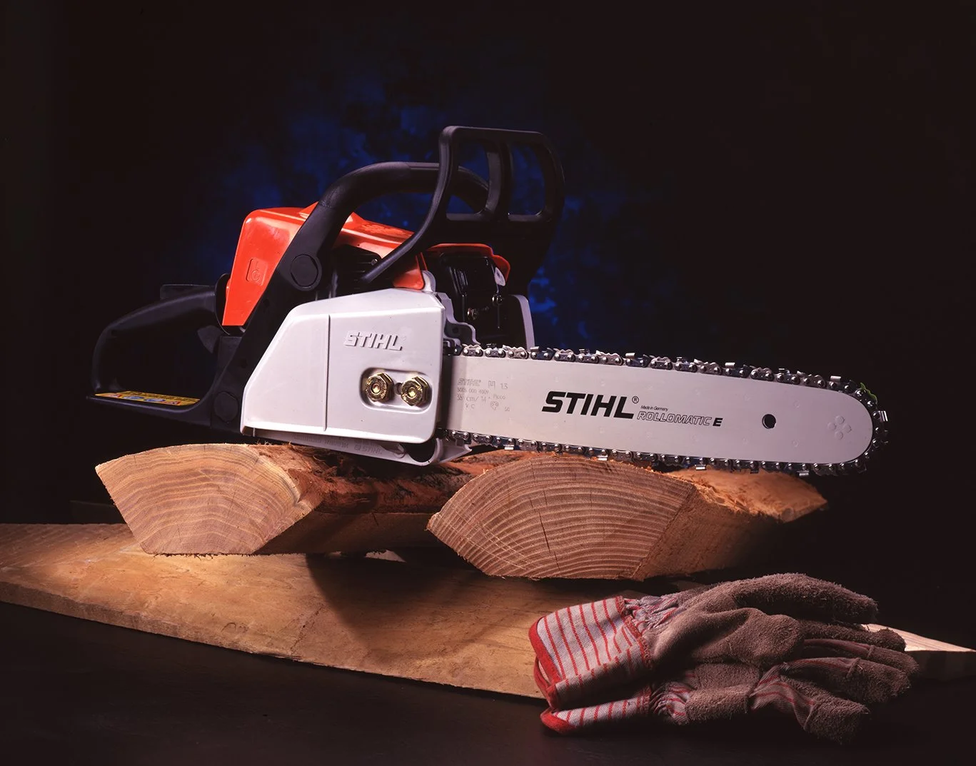 A chainsaw resting on wooden logs, with a pair of work gloves nearby, set against a dark background.
