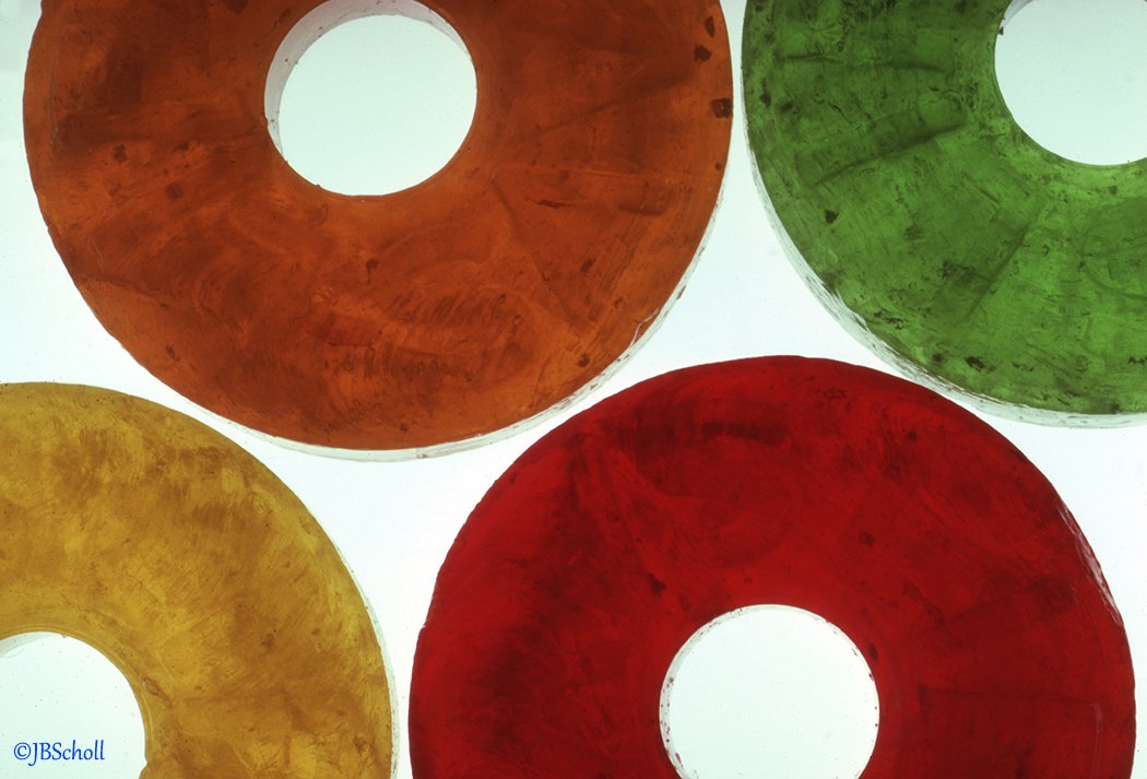 Colorful Lifesavers in red, green, orange, and yellow, viewed from below against a white background.
