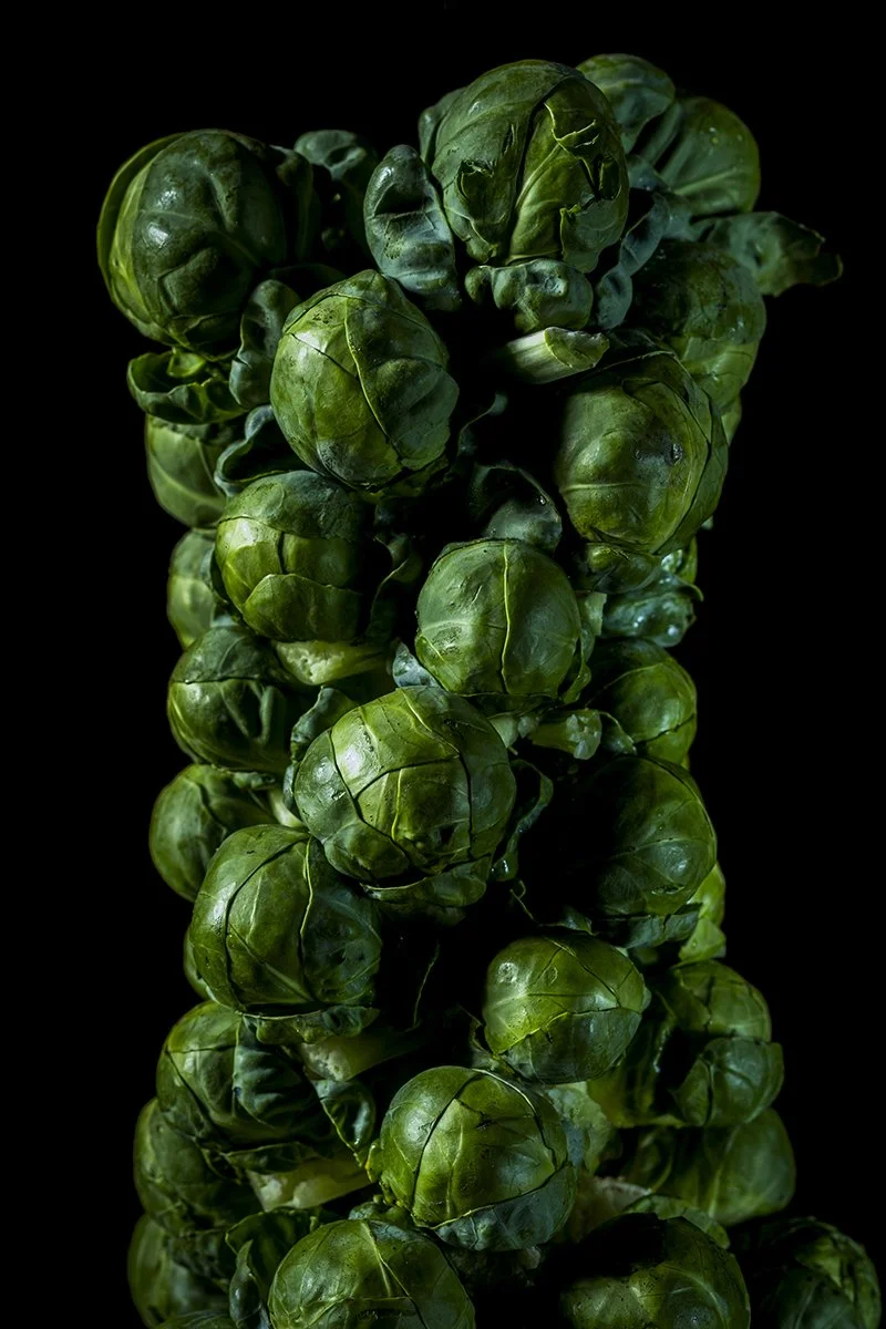 A bunch of Brussels sprouts against a black background.