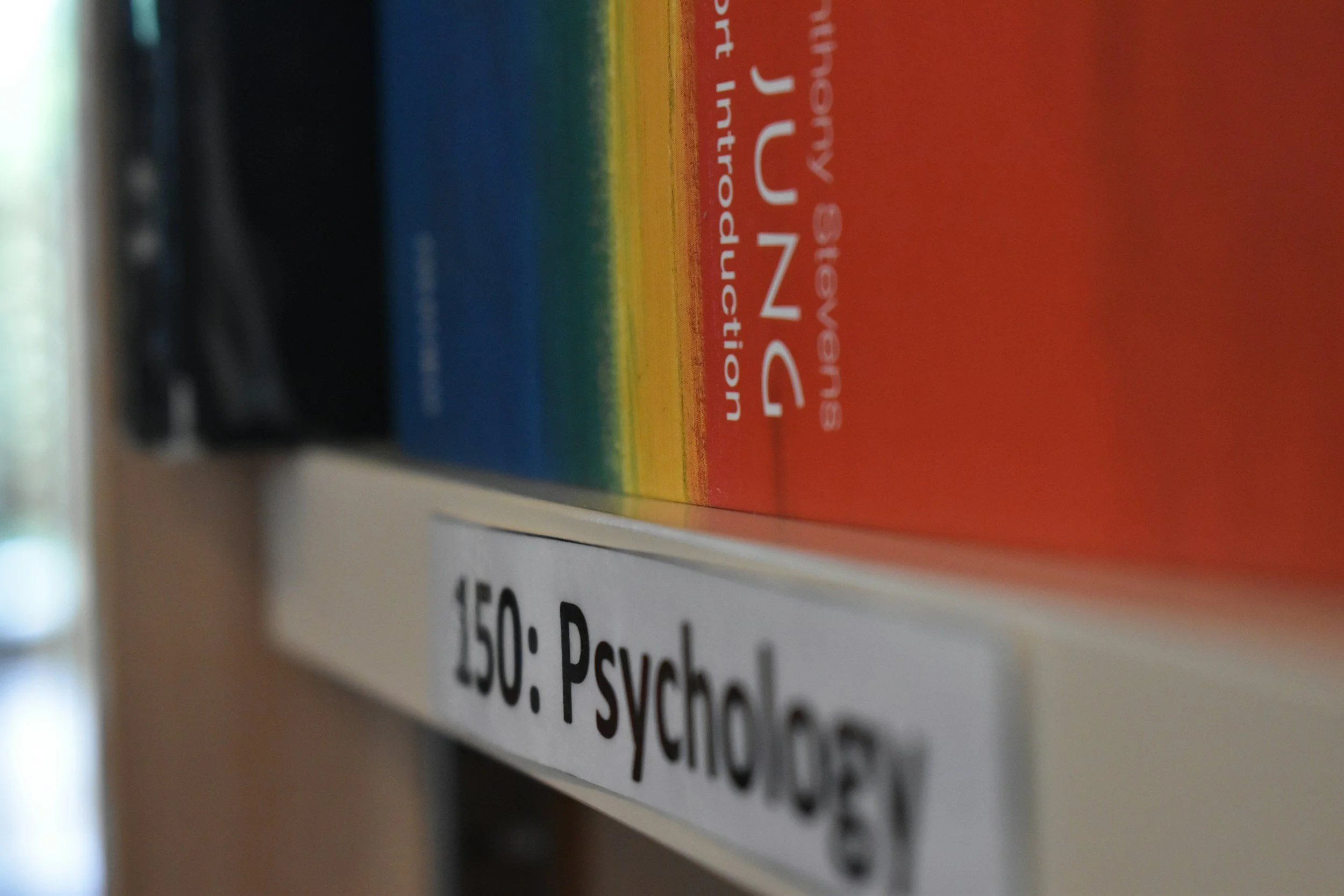 Close-up of a colorful book spine on a shelf with partial text visible, including the words 'psychology'.