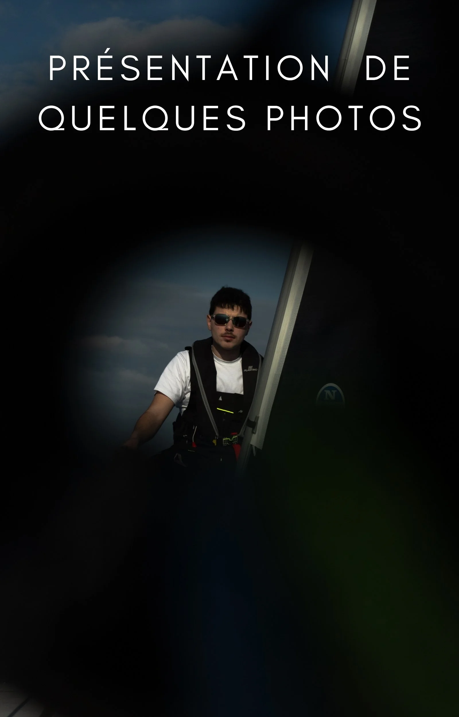 Une photo d'un jeune homme portant des lunettes de soleil, une chemise blanche, avec un sac à dos, en train de prendre une photo ou de prendre possession d'une plateforme de contrôle, avec un ciel nuageux en arrière-plan.