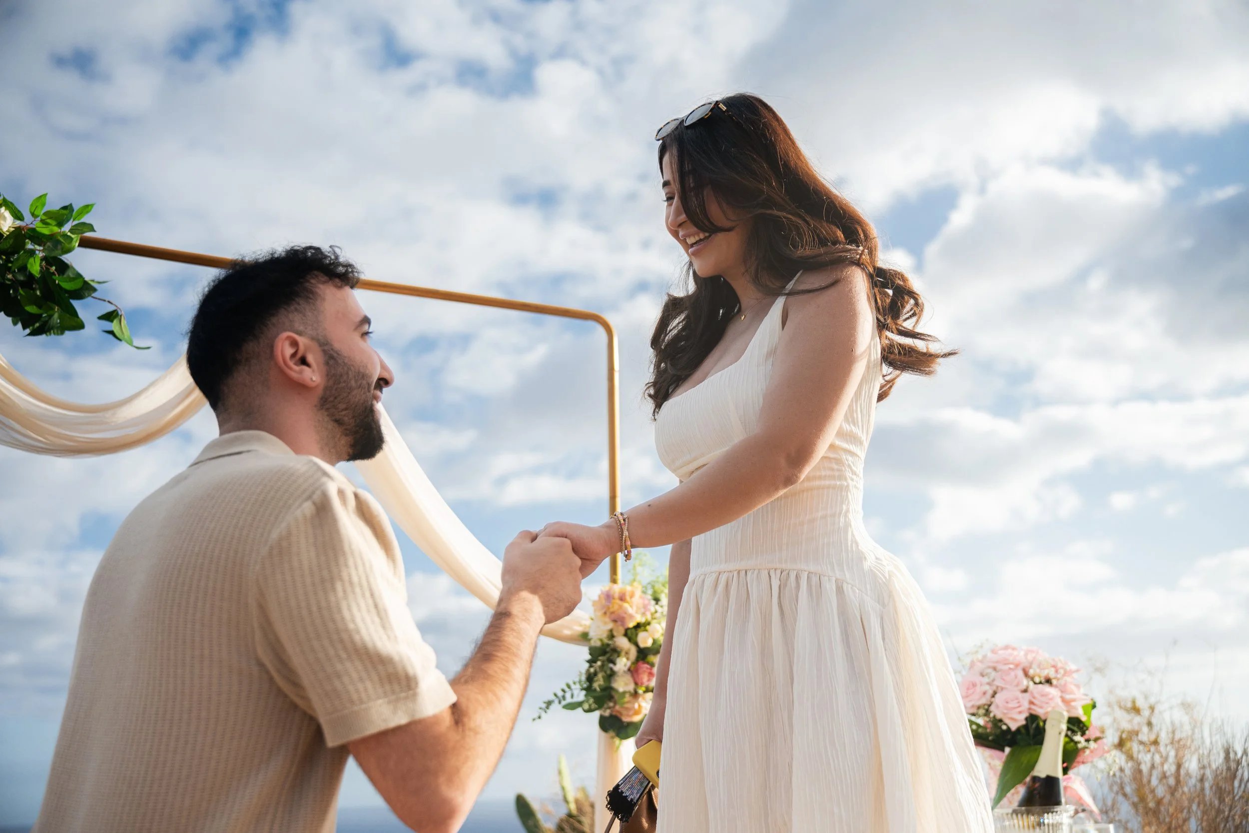 luxury proposal madeira kneeling moment couple holding hands flower arch