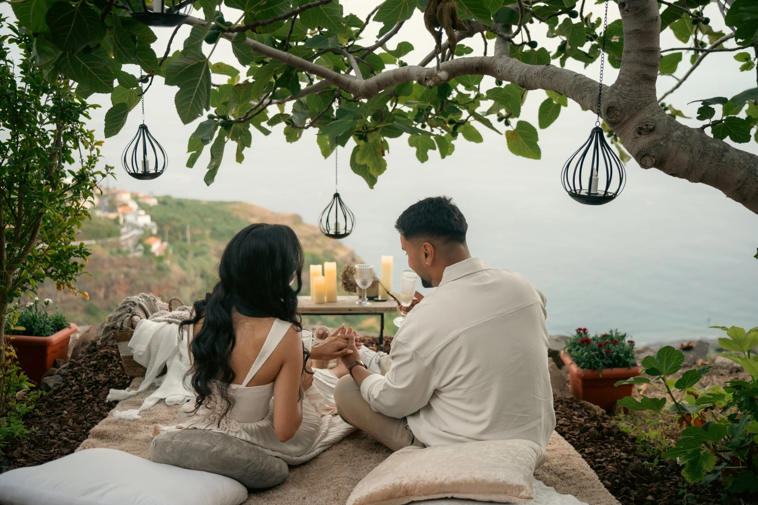 couple sitting under the fig trees at the cliffside orchard admiring the engagement ring