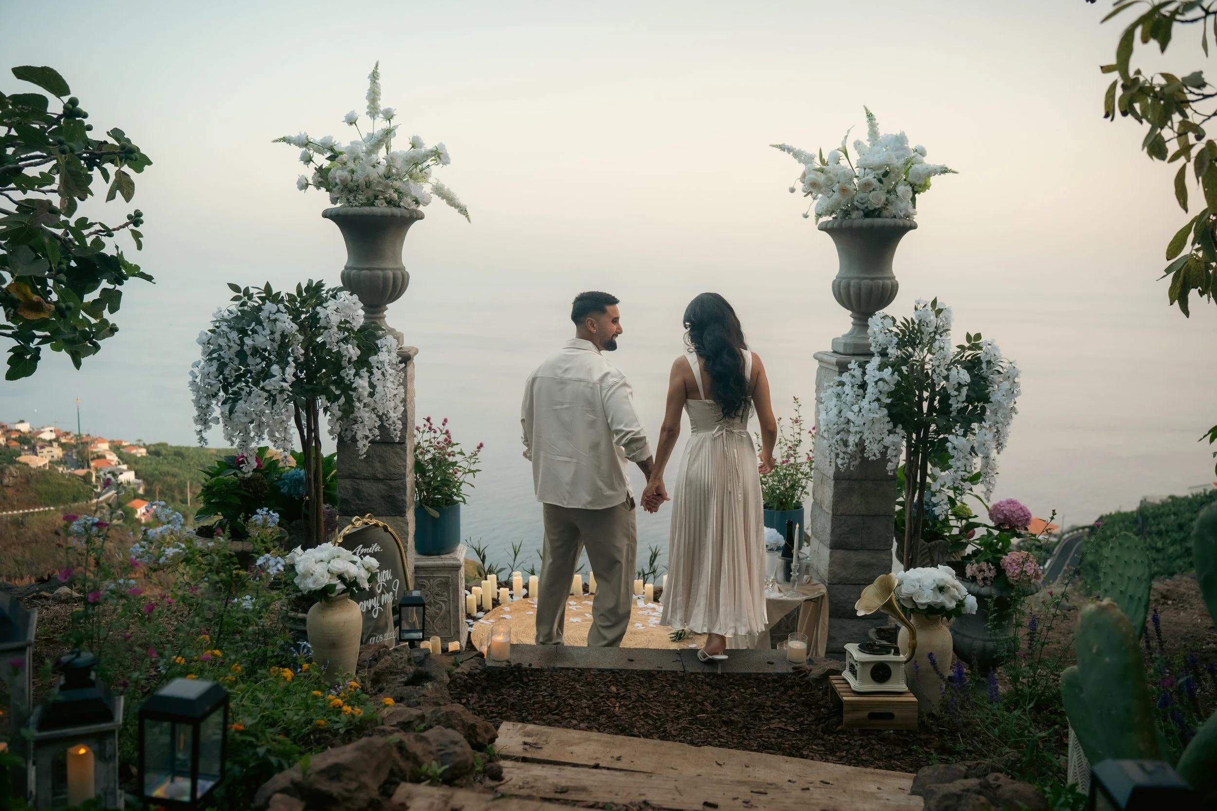 couple walking towards elegant proposal setup in pointa do sol with panoramic seaview