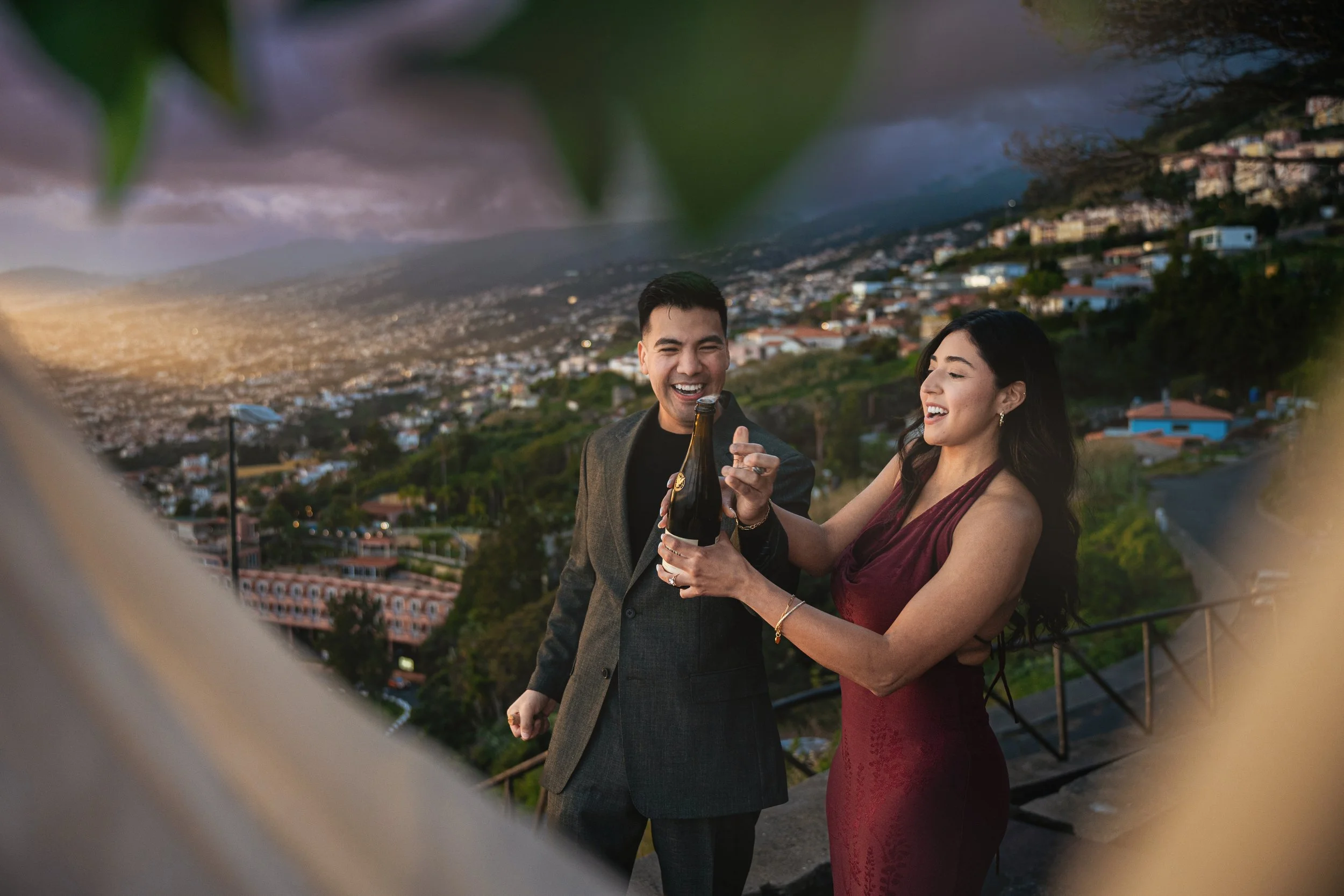 newly engaged couple popping champagne in madeira