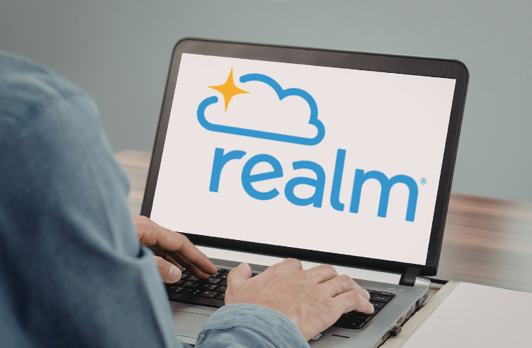 Person using a laptop with the Realm logo on the screen.