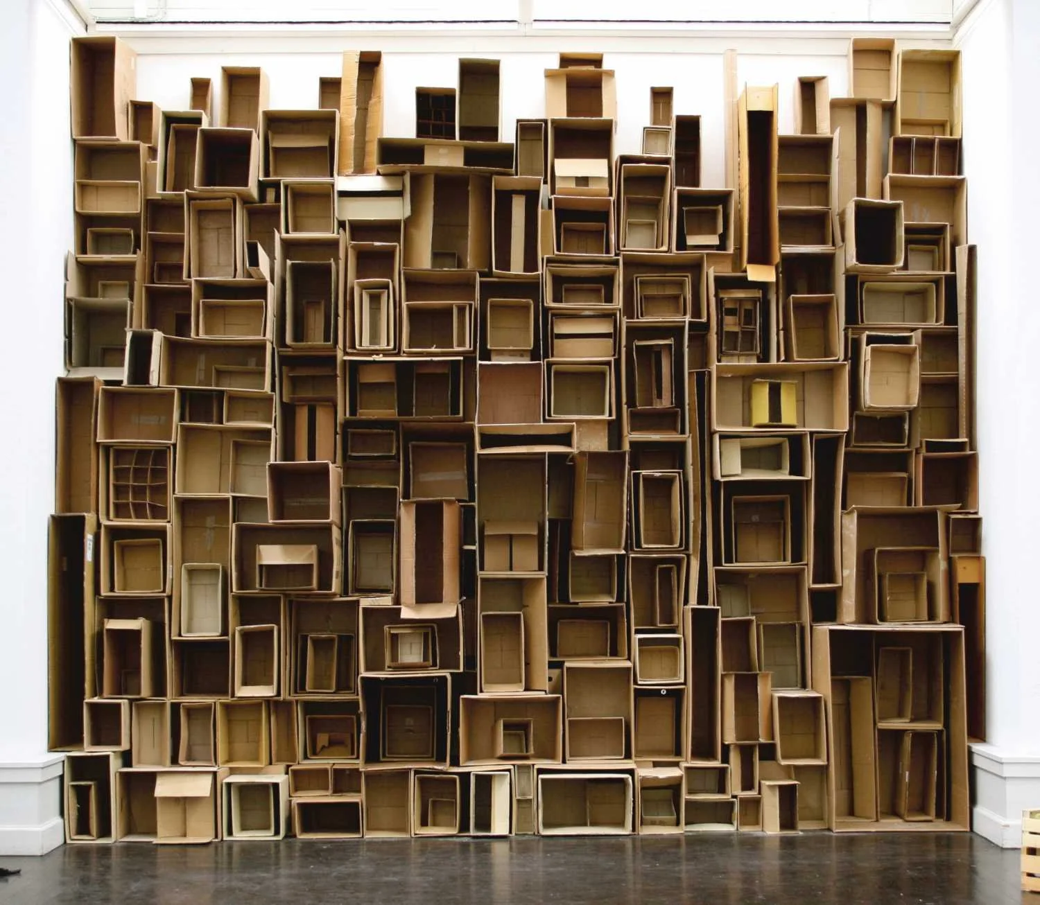 Large installation of empty wooden boxes arranged in a grid pattern on a wall.