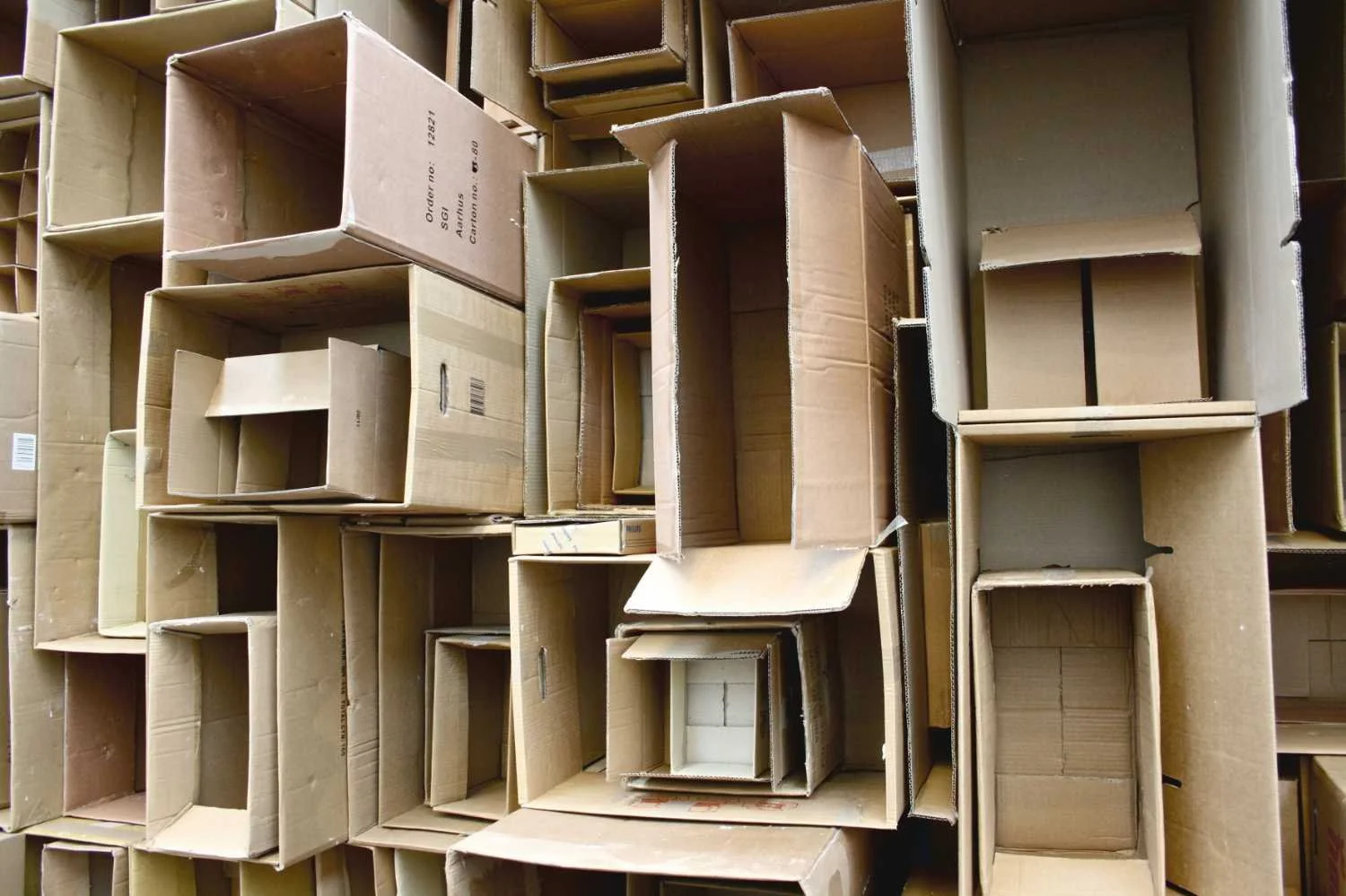 Stacked empty cardboard boxes of various sizes in a storage area.