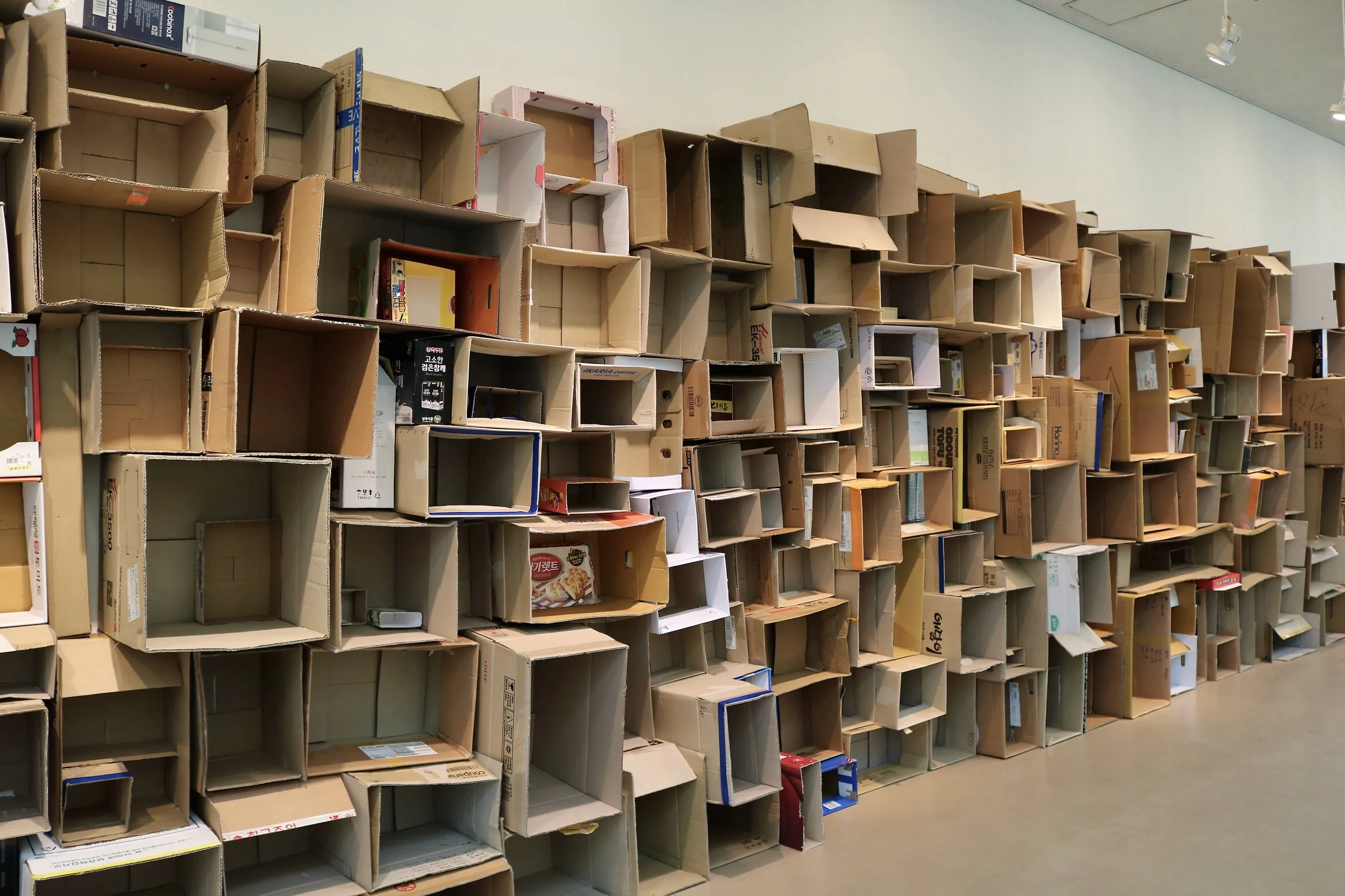 A wall of empty cardboard boxes of various sizes storing or displaying items in a store or warehouse.
