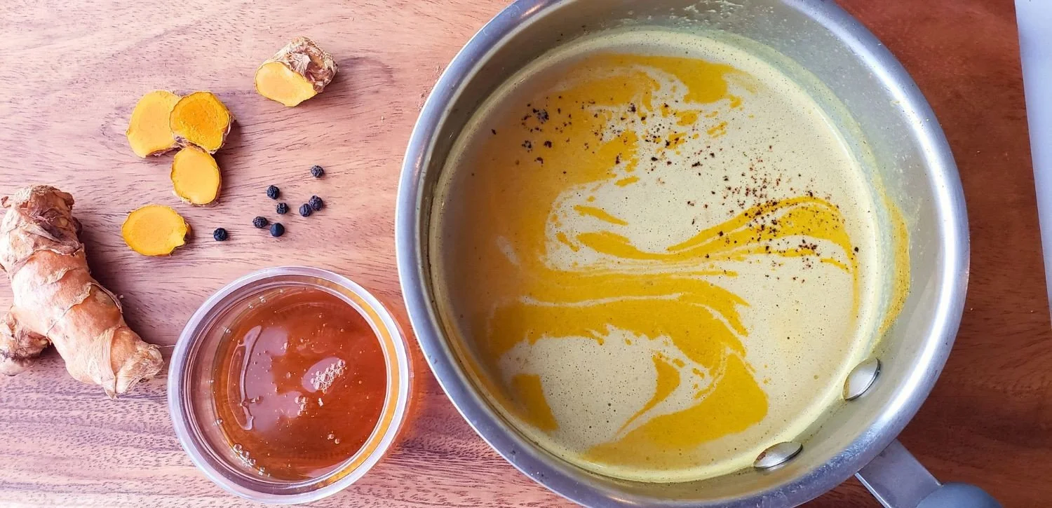 golden milk in pot with fresh turmeric