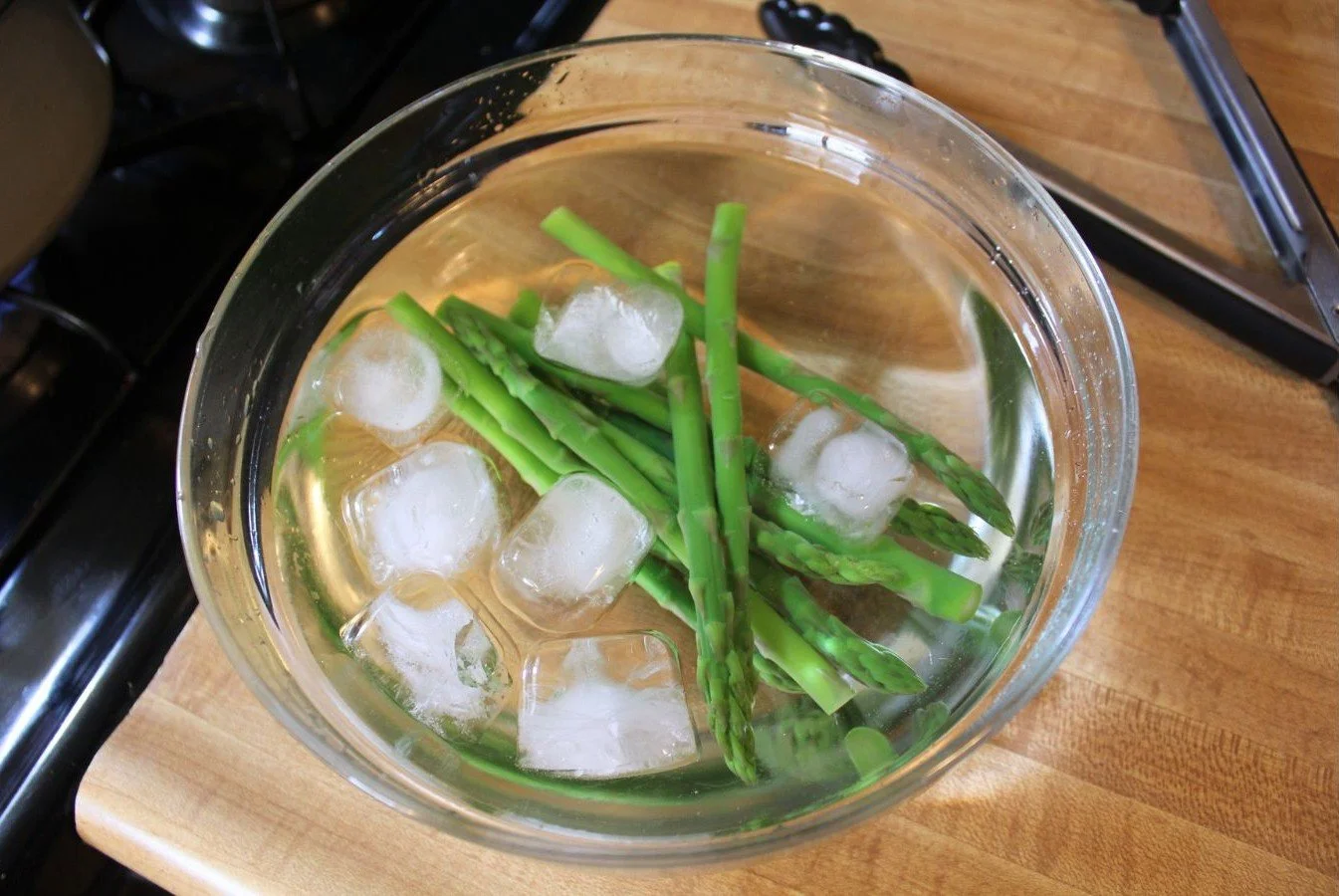 cool blanched asparagus in bowl of ice