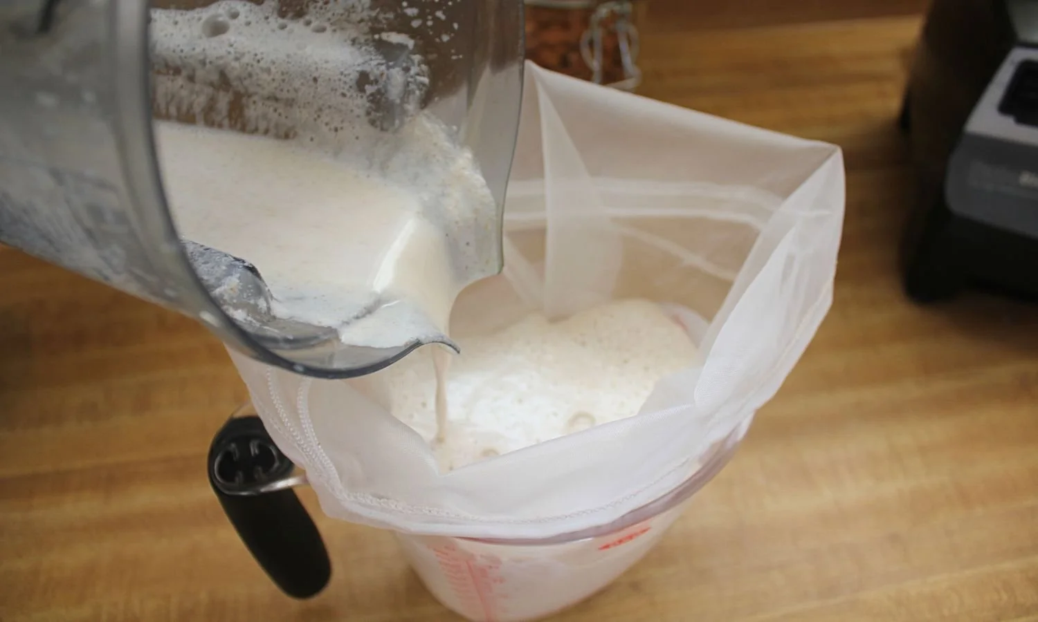 almond milk being strained through nut milk bag