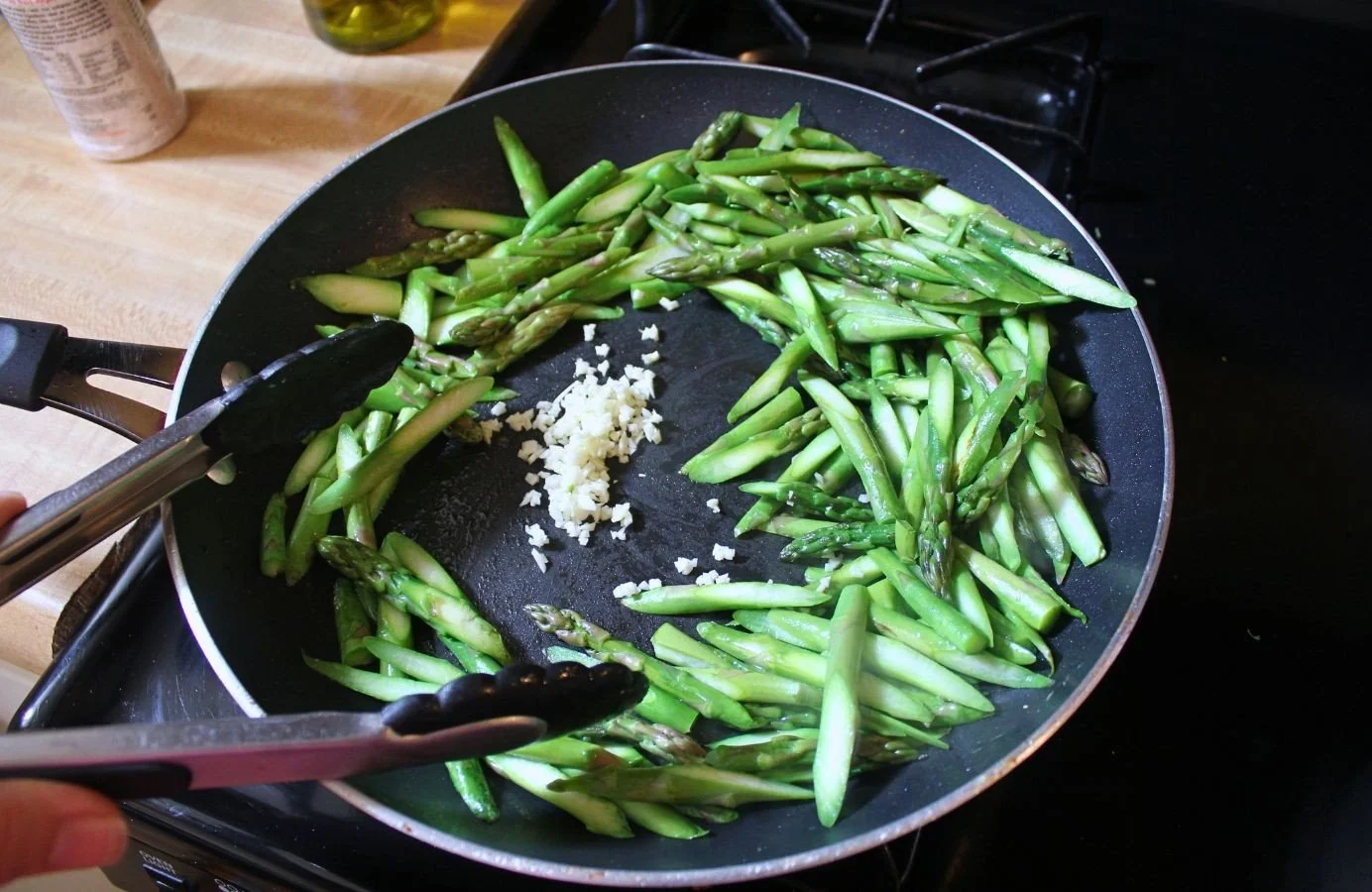 cut asparagus in frying pan with minced garlic