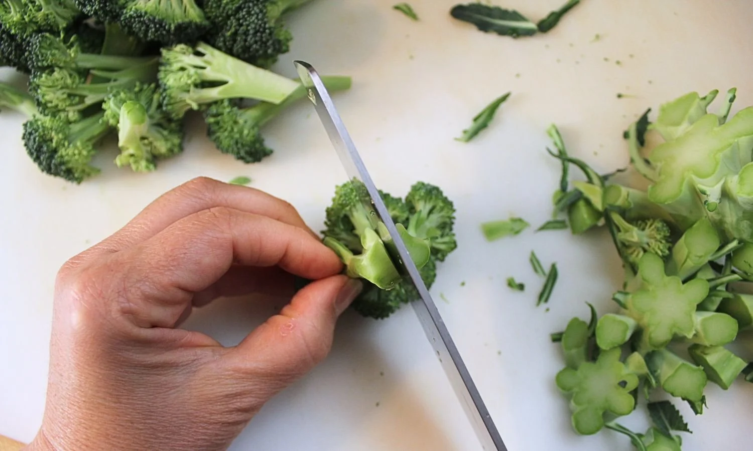 trimming broccoli on cutting board