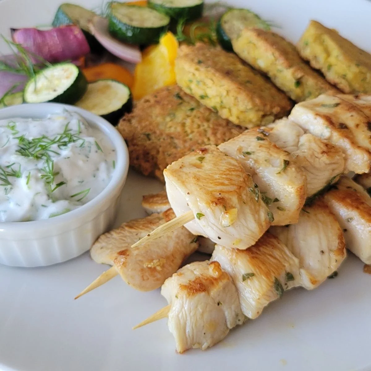 chicken souvlaki on plate with tzatziki falafel and zucchini