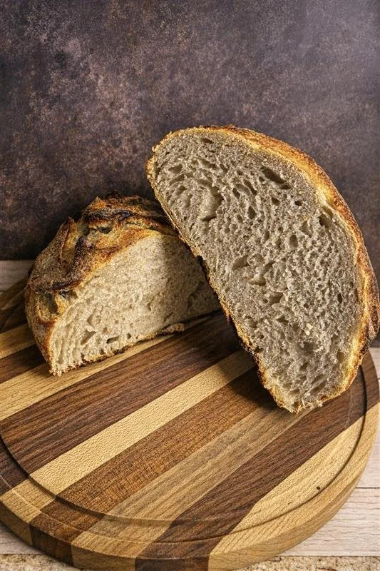 A loaf of sliced bread on a wooden cutting board, showing the soft interior and crust.